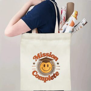 Person carrying a “Mission Complete” graduation tote bag over the shoulder, with rolled posters and graduation essentials.