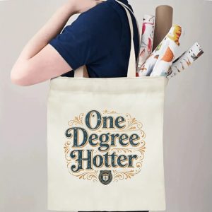 Person carrying a “One Degree Hotter” graduation tote bag over the shoulder, with rolled posters and graduation essentials.