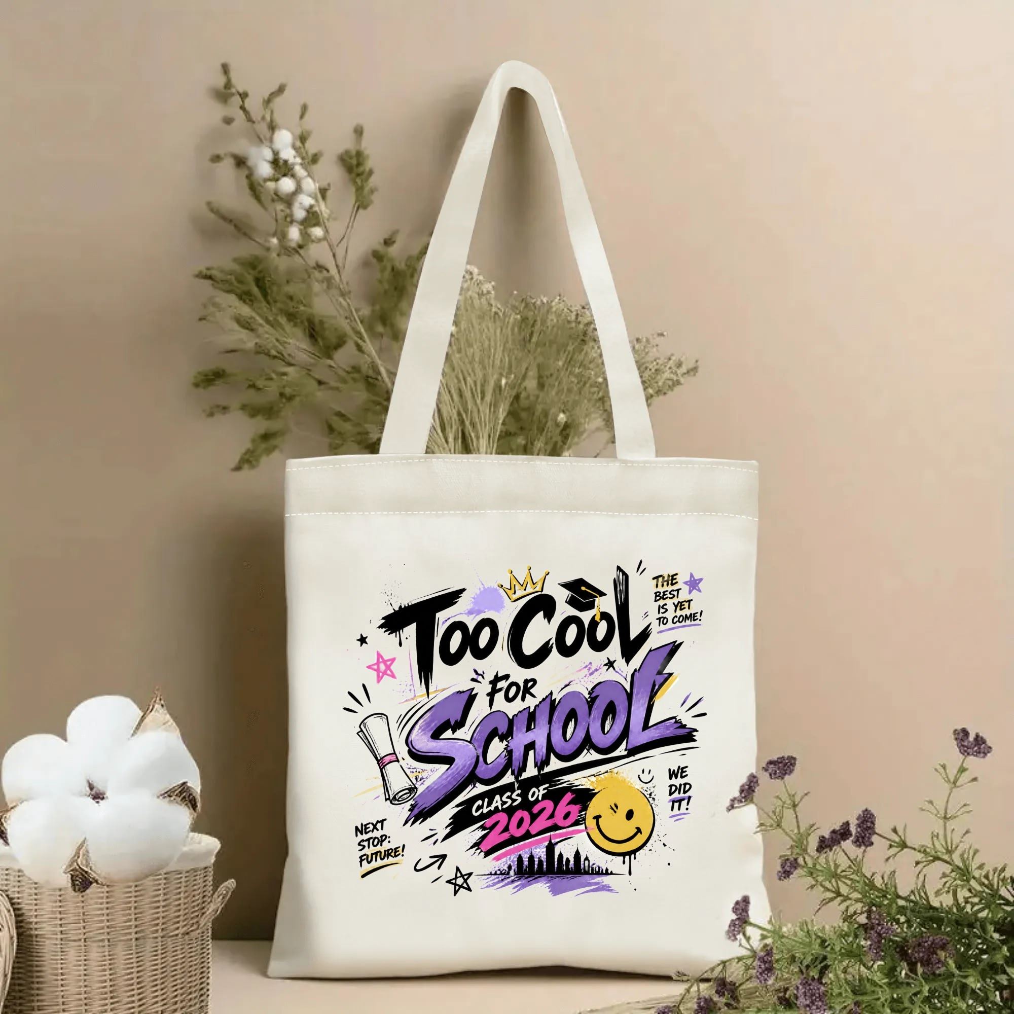 Natural canvas tote bag with “Too Cool For School Class of 2026” print, featuring a graffiti-style design, graduation cap, crown, diploma, and smiley face in purple, black, and pink.