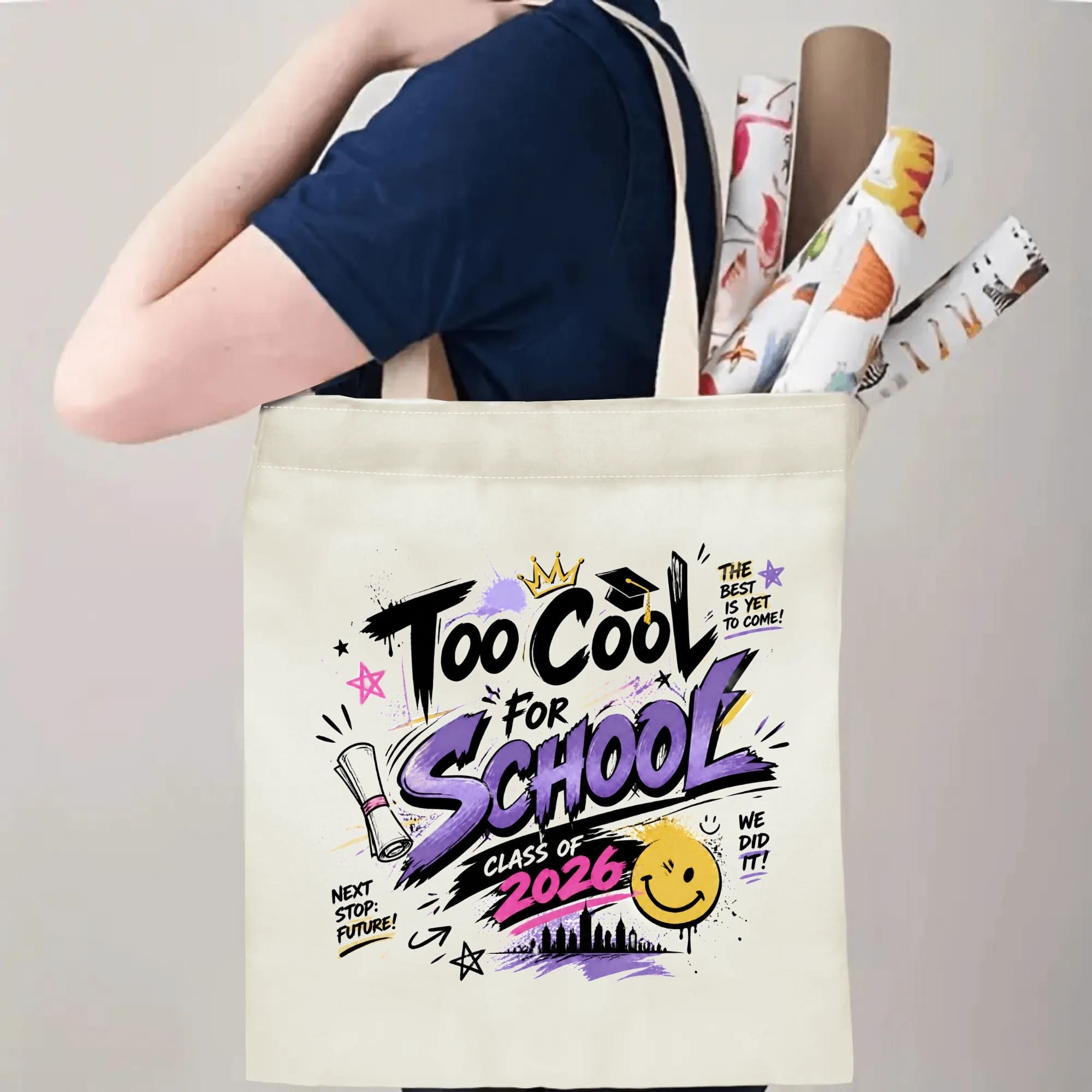 Person carrying a “Too Cool For School Class of 2026” graduation tote bag over the shoulder, with rolled posters and graduation essentials.