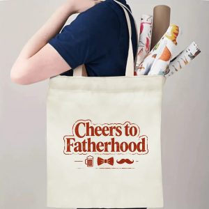 Person carrying a “Cheers to Fatherhood” Father’s Day tote bag over the shoulder, perfect for casual dad outings and errands.