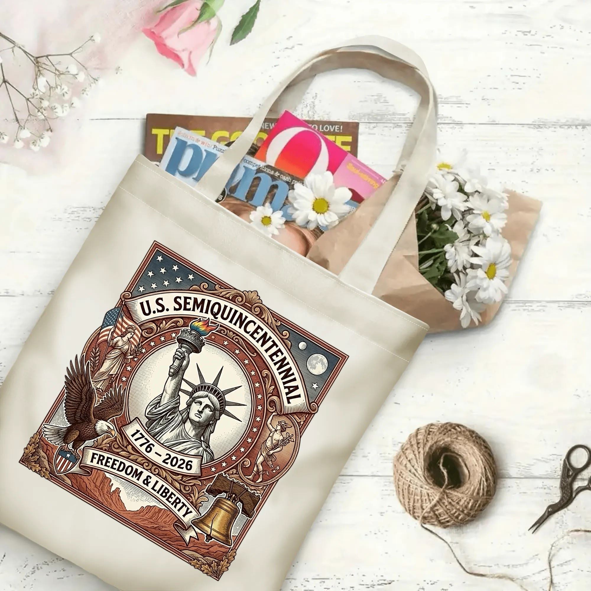 Patriotic printed canvas tote laid flat on wooden table, filled with magazines and fresh daisies to show daily storage capacity.