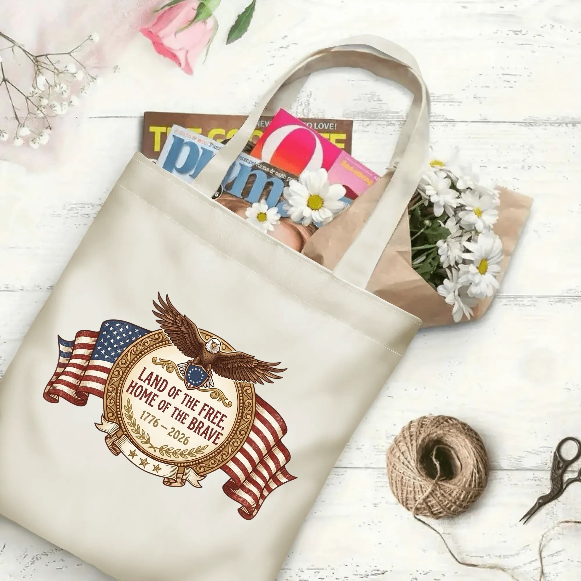 Patriotic eagle flag canvas tote laid flat on wooden table, stuffed with magazines and fresh flowers to show large daily capacity.