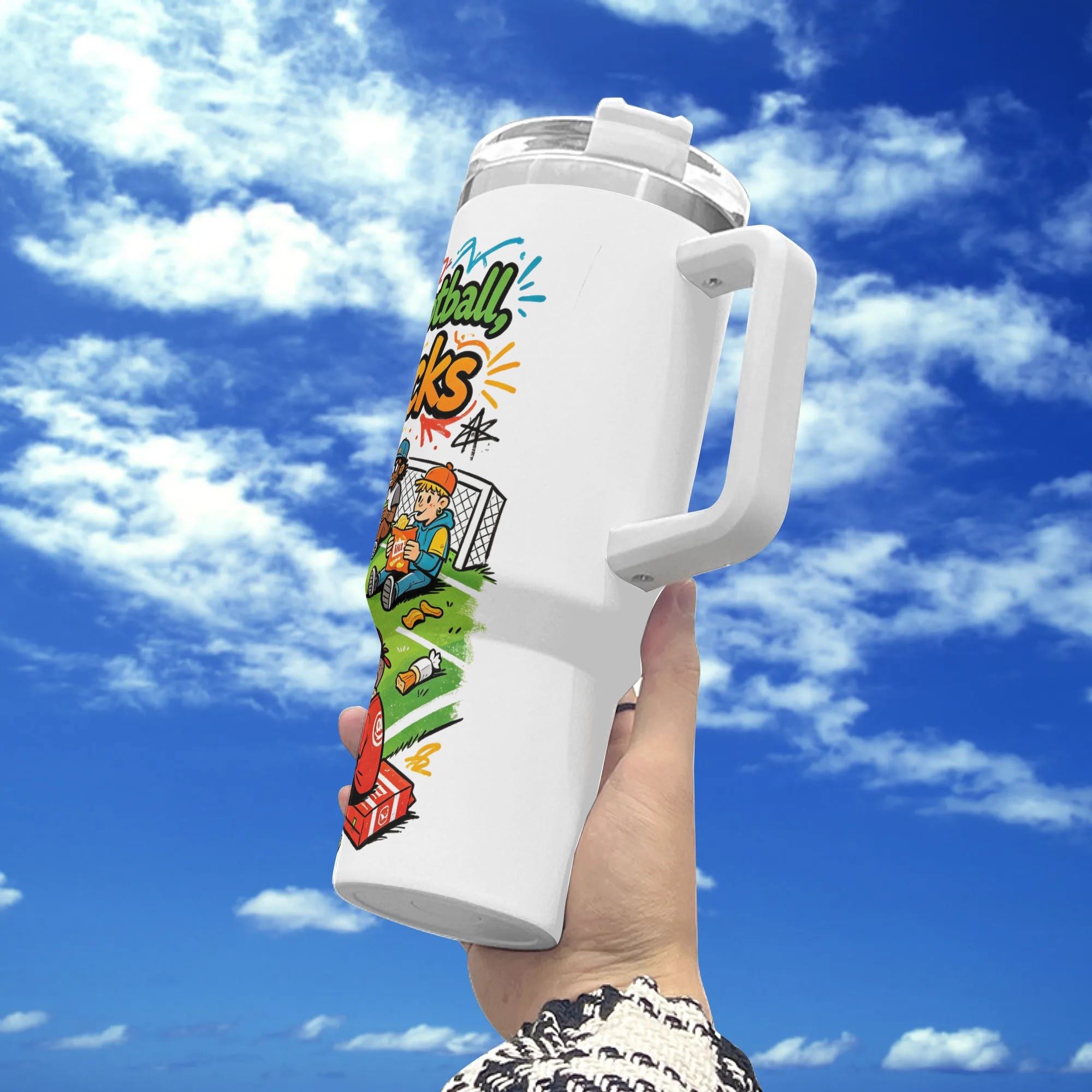 White 40oz insulated stainless steel tumbler with handle, fun retro‑cartoon "90 Minutes of Football, 90% Snacks" soccer fan snack‑themed print, held against blue sky background, playful casual sports fan travel mug