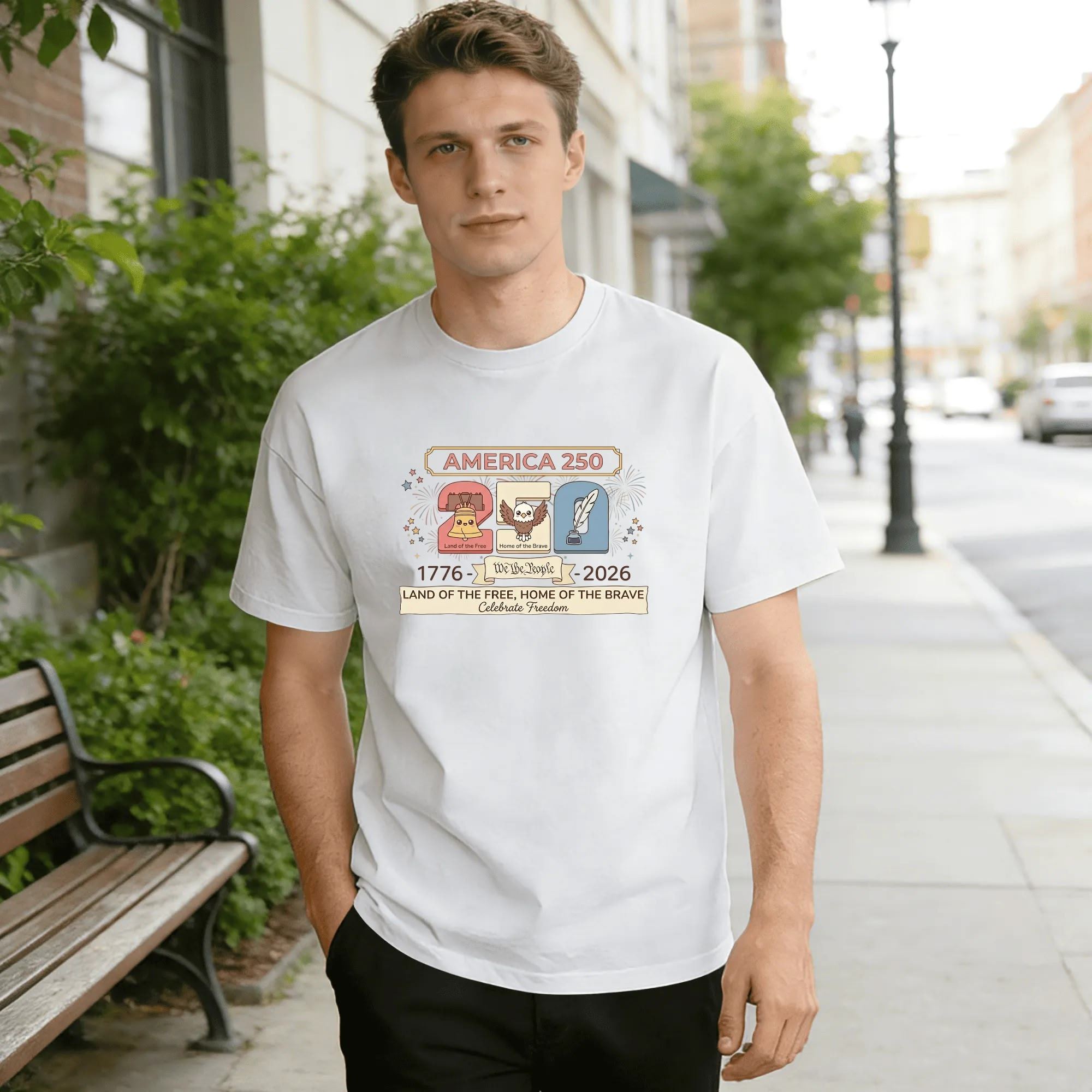 Young man wearing white relaxed‑fit cotton tee with soft retro cartoon America 250 graphic, liberty bell, bald eagle, quill pen forming “250”, “We the People” banner, 1776‑2026 founding dates, “Land of the Free Home of the Brave” slogan, star‑firework accents, gentle vintage style, street‑style outdoor lifestyle shot, sweet USA 250th anniversary commemorative apparel