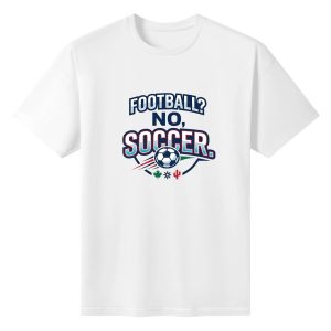 White oversized cotton short‑sleeve t‑shirt, front athletic varsity‑style stacked‑text “Football? No, Soccer.” typography print with soccer ball, dynamic speed‑lines and regional North‑America decorative icons, casual pro‑soccer sports‑themed tee flat lay