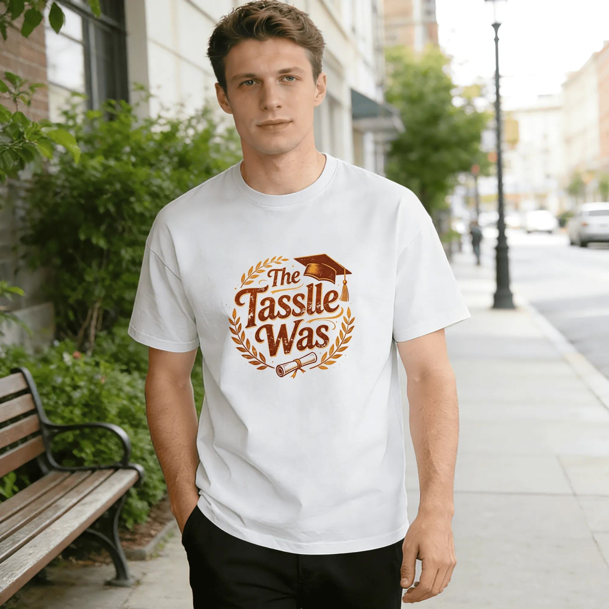 Model wearing the white “The Tassle Was” laurel wreath graduation tee outdoors, showcasing the relaxed fit and retro-inspired design.
