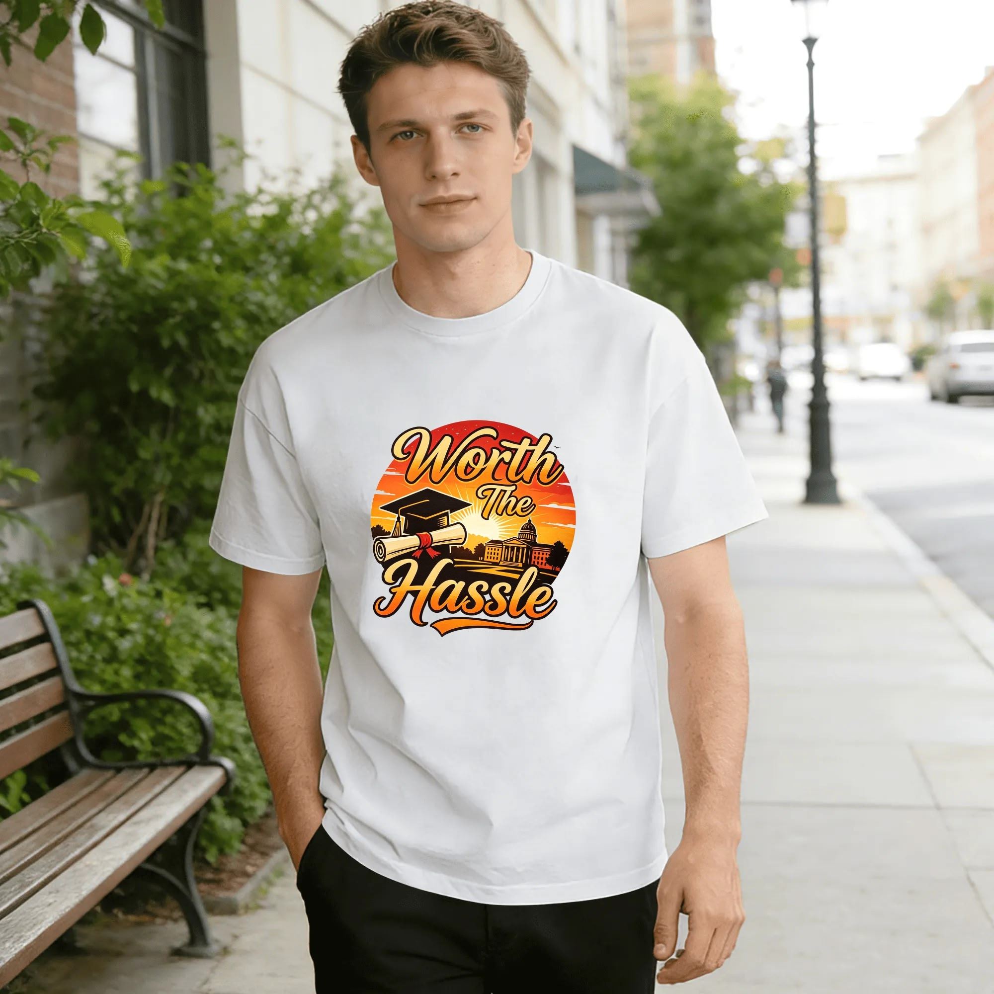 Model wearing the white “Worth The Hassle” graduation tee outdoors, showcasing the relaxed fit and vibrant retro-inspired design.