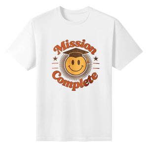 Black crewneck T-shirt with a retro “Mission Complete” graphic, featuring a smiley face in a graduation cap, distressed orange lettering, and star accents.