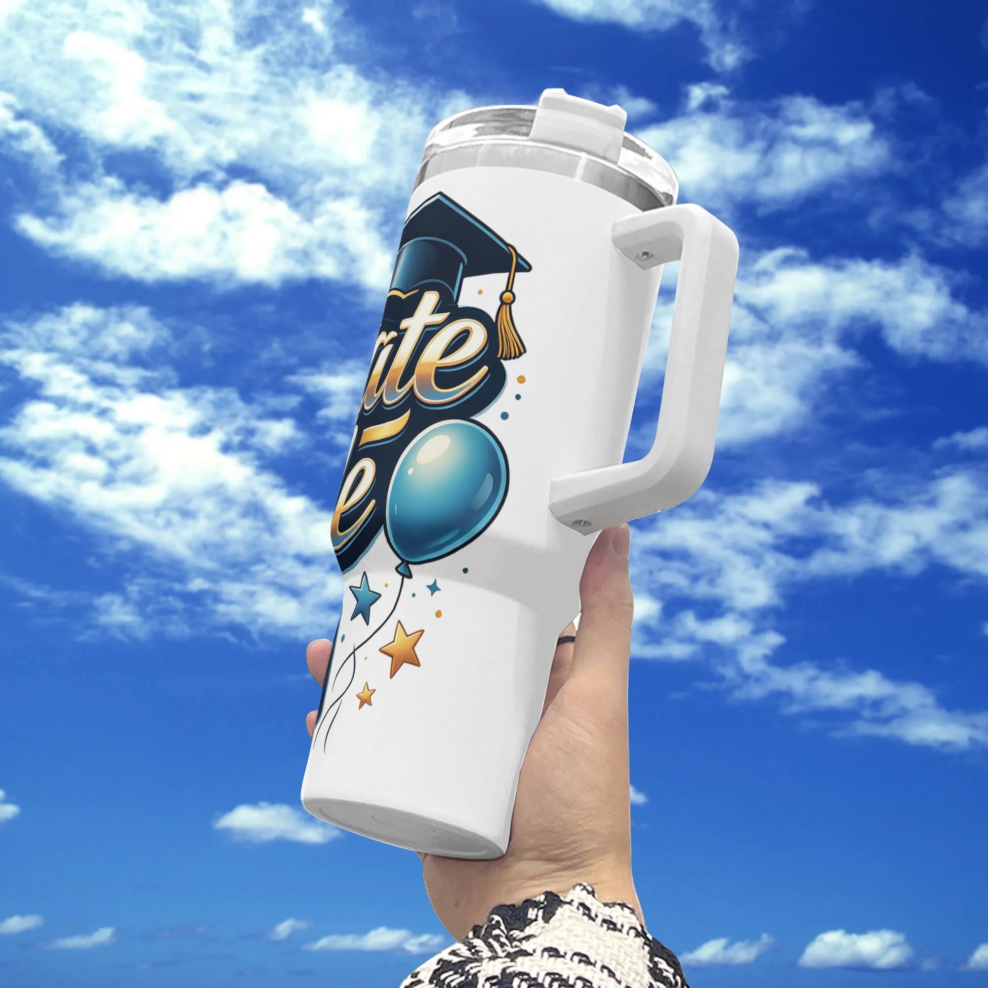 40oz white stainless steel tumbler with handle, featuring a "Graduate Mode ON" graduation design with cap, balloon, and stars, held against a bright sky.