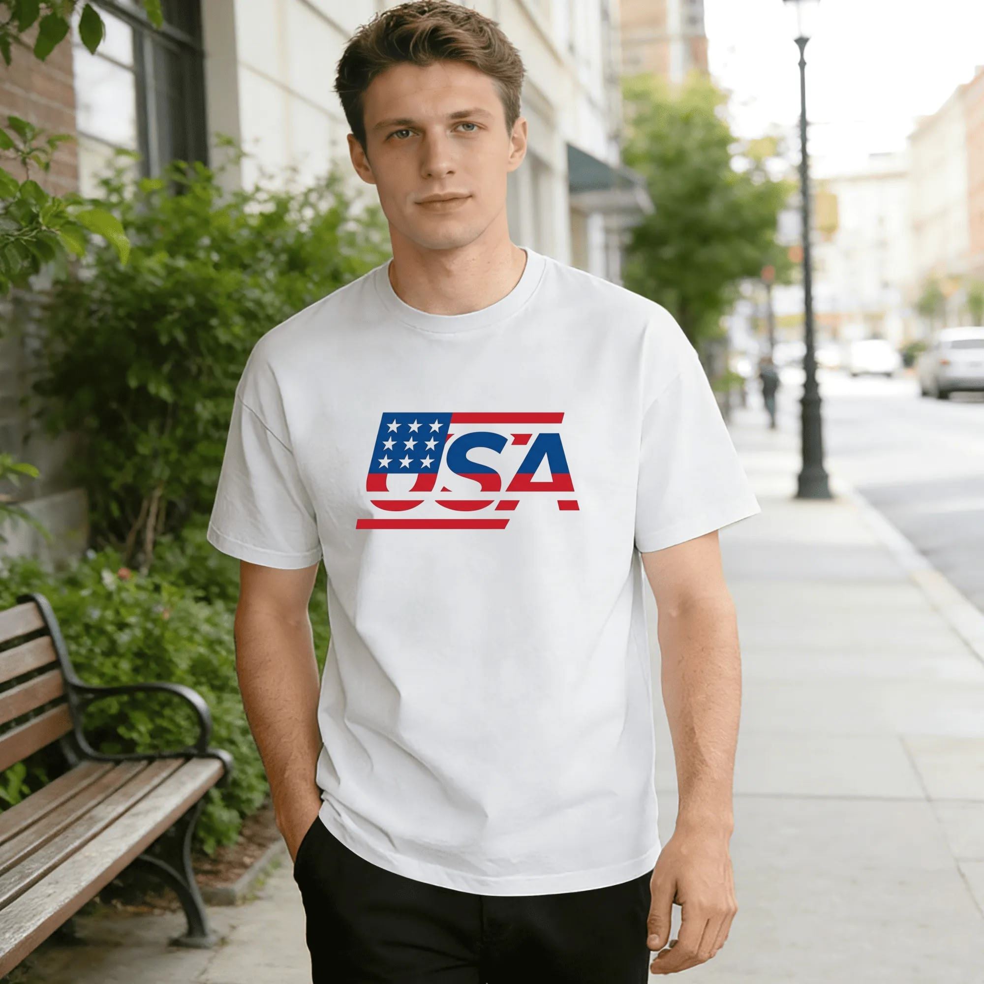 Male model on city sidewalk wearing white casual short sleeve tee with minimalist stars & stripes USA letter print.