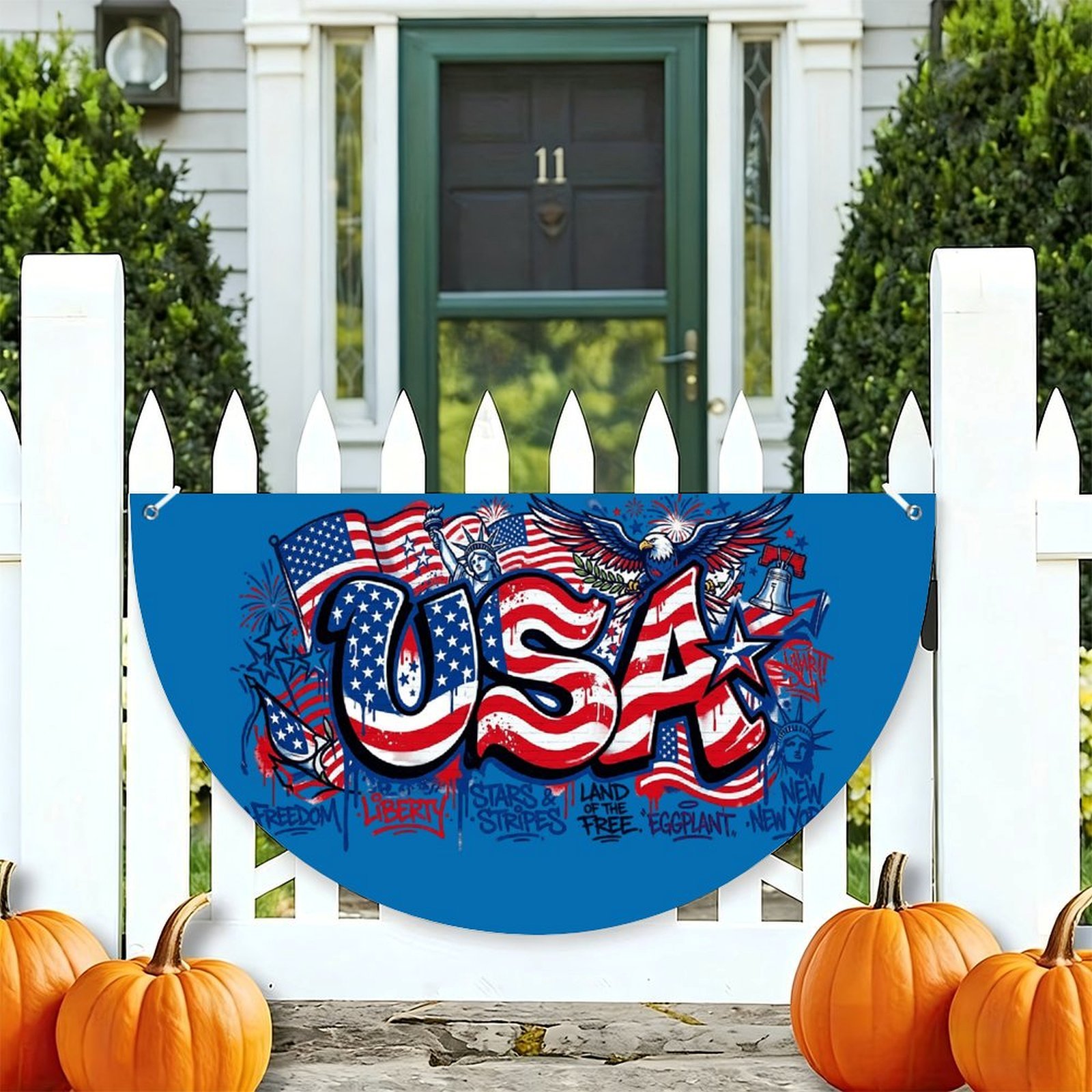 Blue half-circle “USA” patriotic banner hung on a white picket fence, featuring graffiti-style American symbols, perfect for 4th of July or patriotic outdoor decor.
