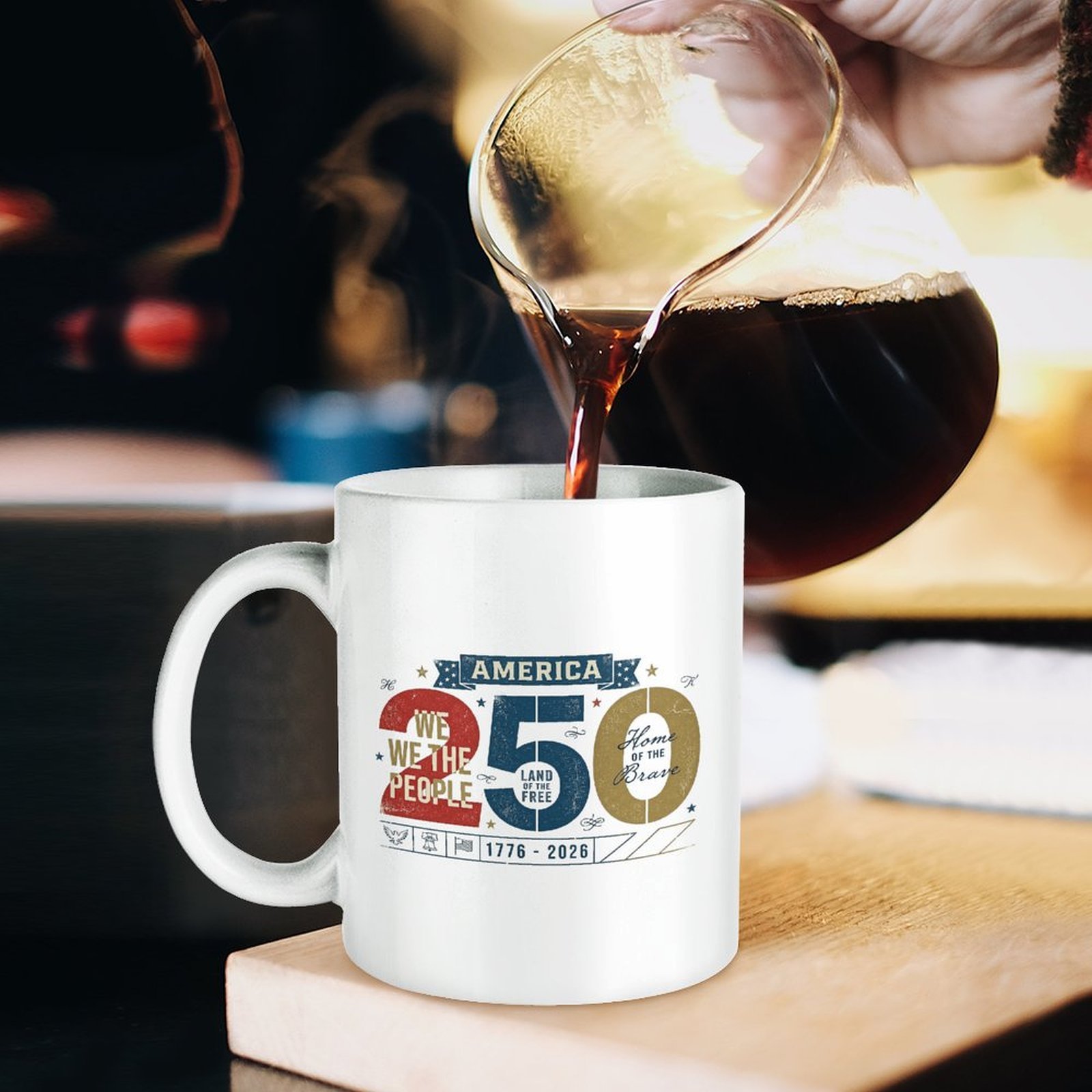 Lifestyle pouring coffee shot: white patriotic printed ceramic mug on wooden board as fresh black coffee is poured into cup.