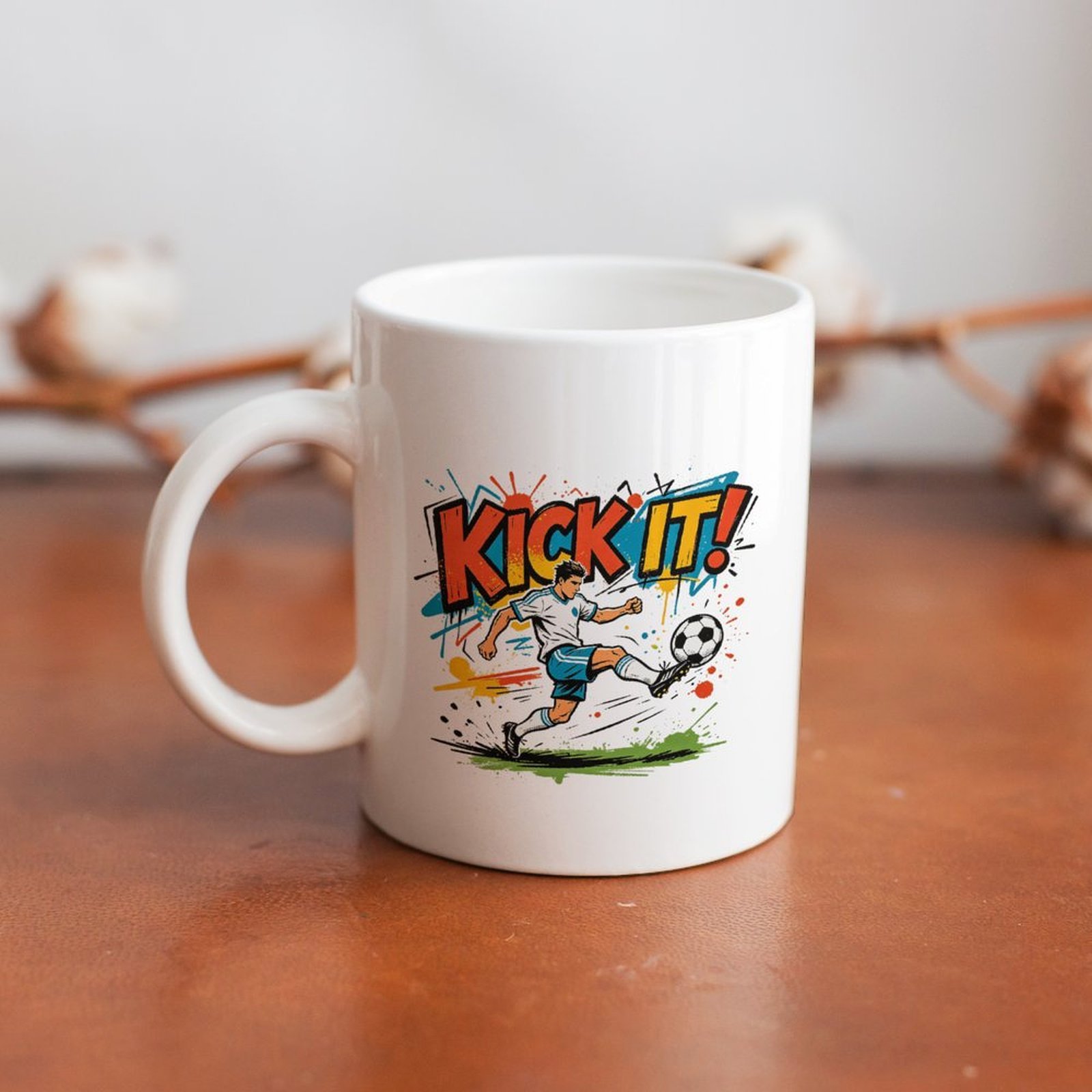 White 11oz ceramic coffee mug with “KICK IT!” soccer player print, laid flat on a wooden table, perfect for soccer fan daily use.