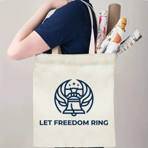 Person carrying winged Liberty Bell Let Freedom Ring printed canvas shoulder bag, everyday reusable patriotic shopping tote