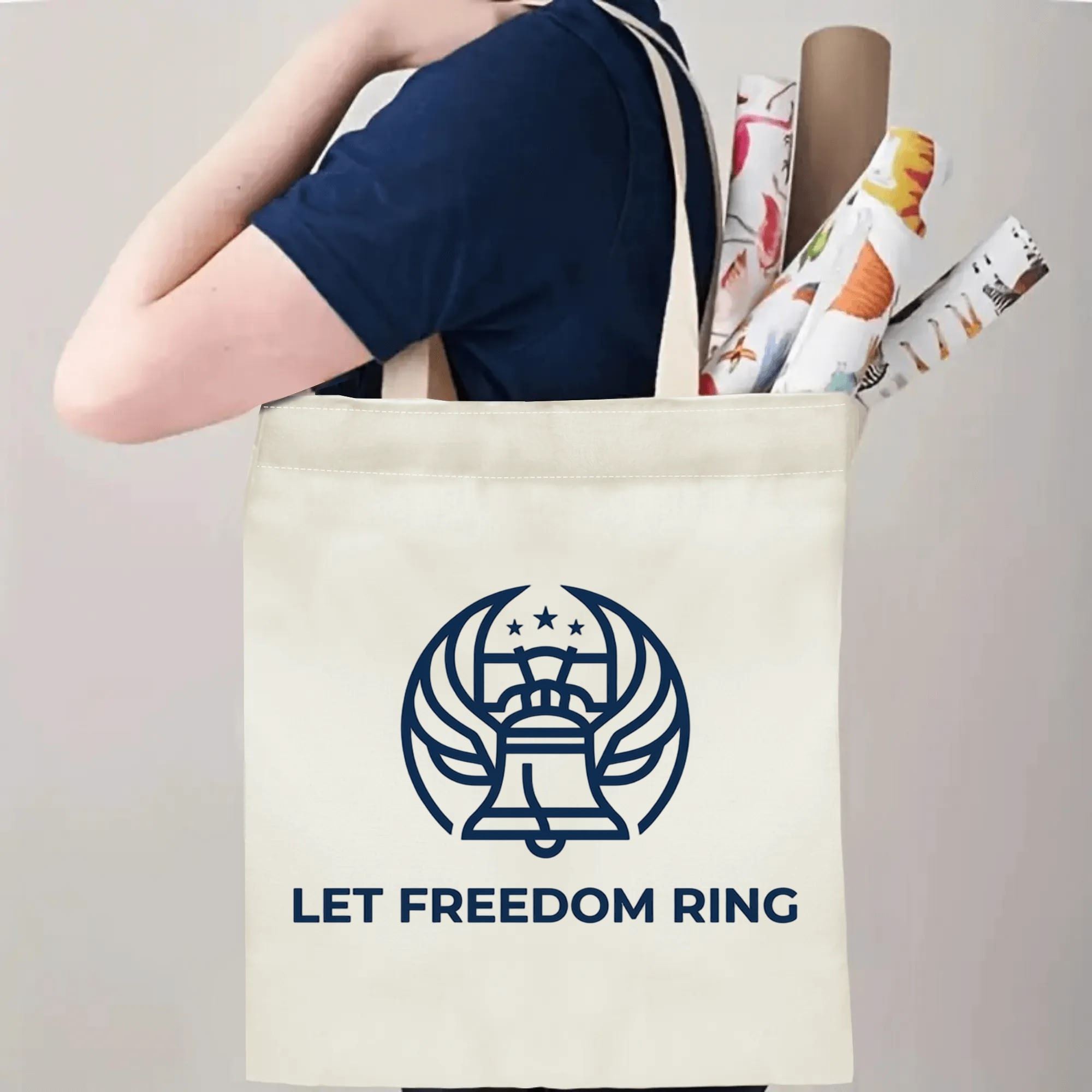 Person carrying winged Liberty Bell Let Freedom Ring printed canvas shoulder bag, everyday reusable patriotic shopping tote