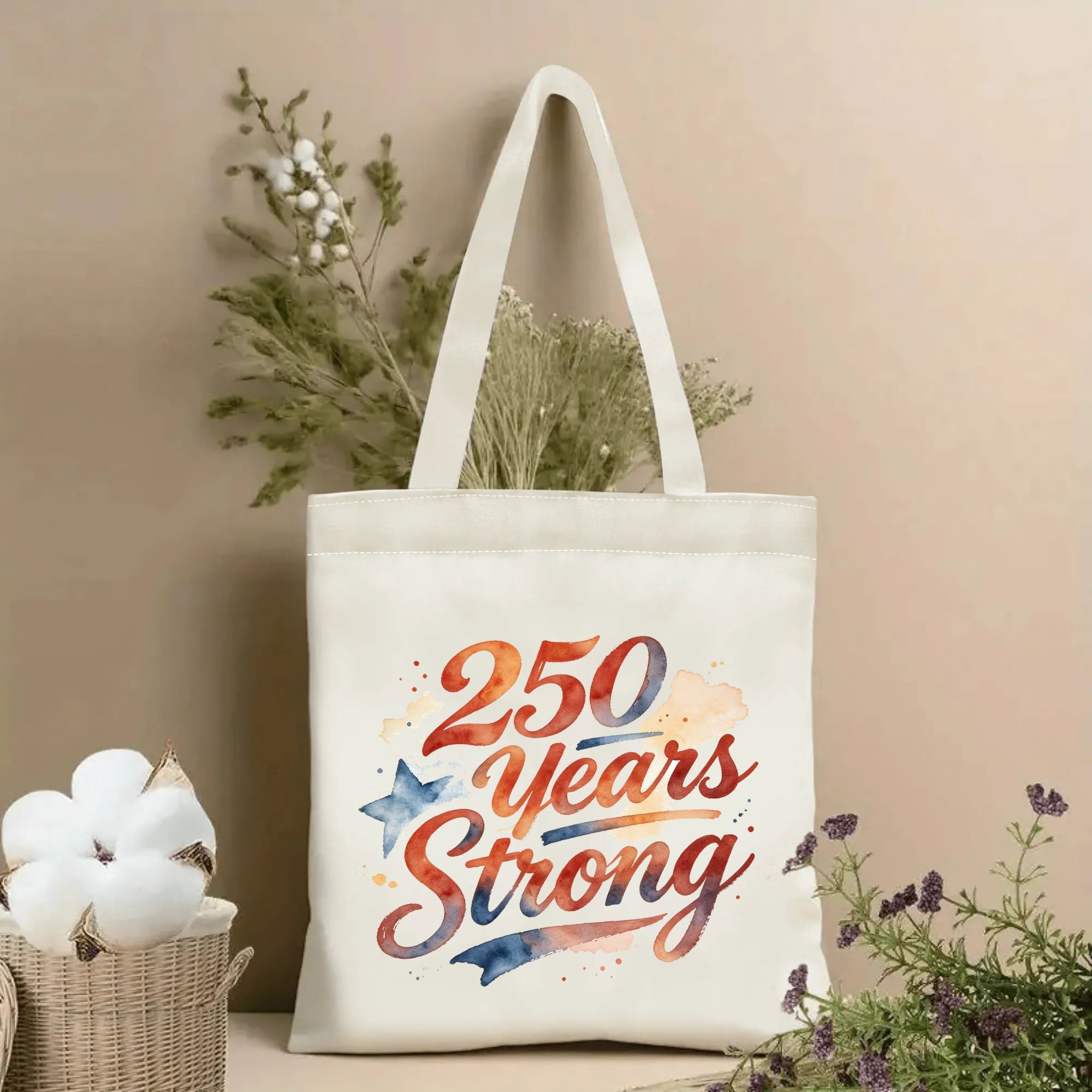 Tote bag with watercolor “250 Years Strong” print, styled with dried flowers