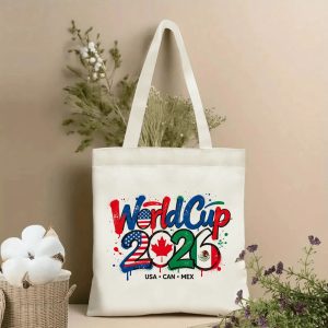 Lifestyle shot of the tote bag featuring a graffiti-style “World Cup 2026” print, where the numbers “2026” incorporate the flags of the USA, Canada, and Mexico, displayed against a neutral background with plants.
