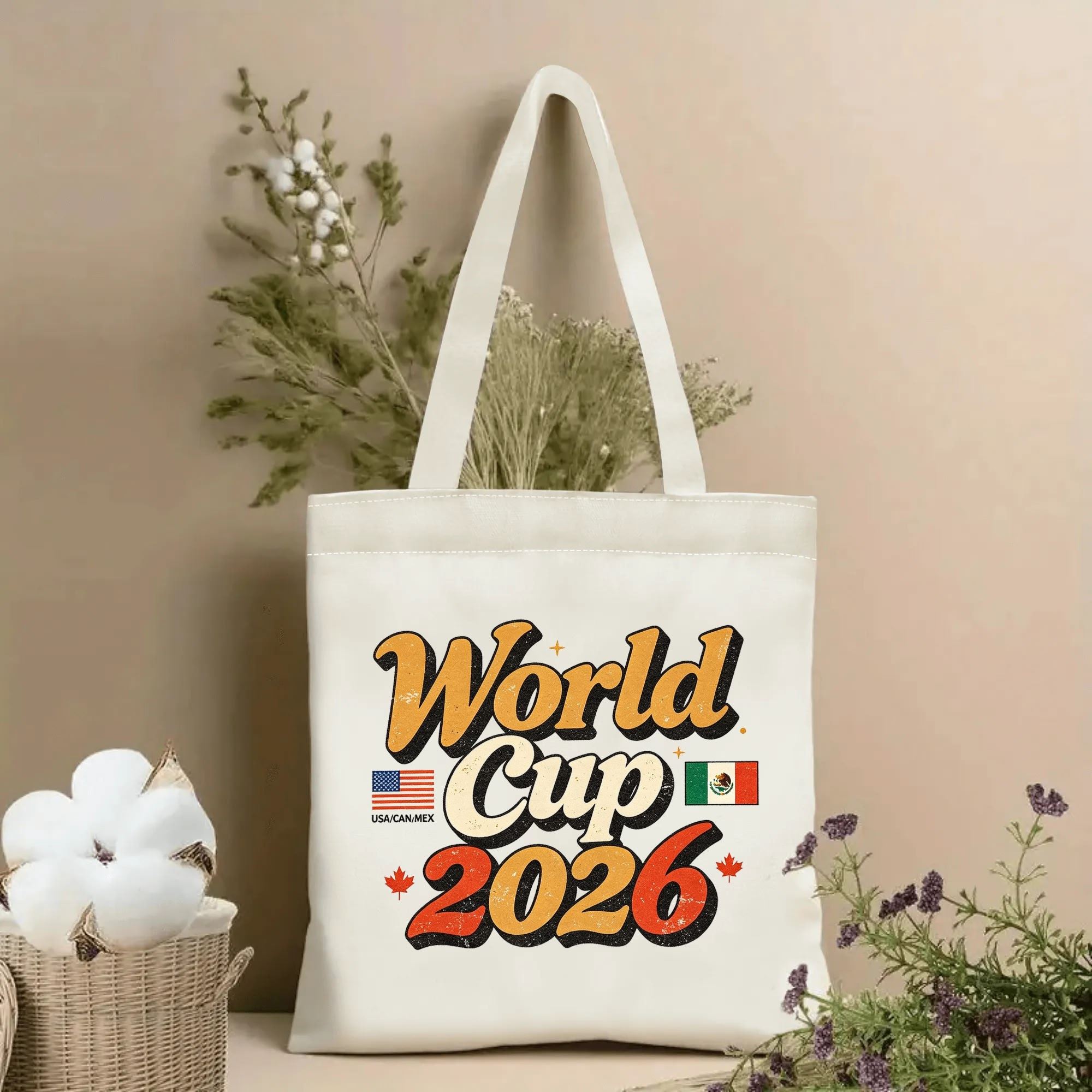 Lifestyle shot of the tote bag featuring a retro “World Cup 2026” print, with 70s-style script, host country flags (USA, Mexico) and Canadian maple leaves, displayed against a neutral background with plants.
