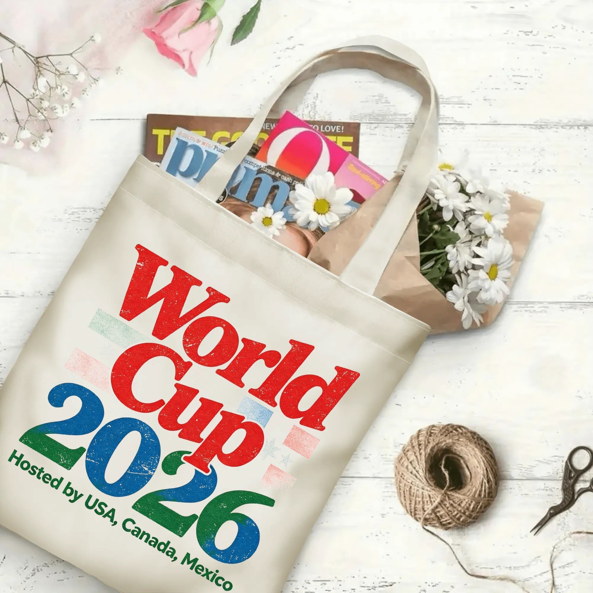 The tote bag in use, filled with books and flowers, showing the "World Cup 2026" distressed print in a casual, everyday setting.