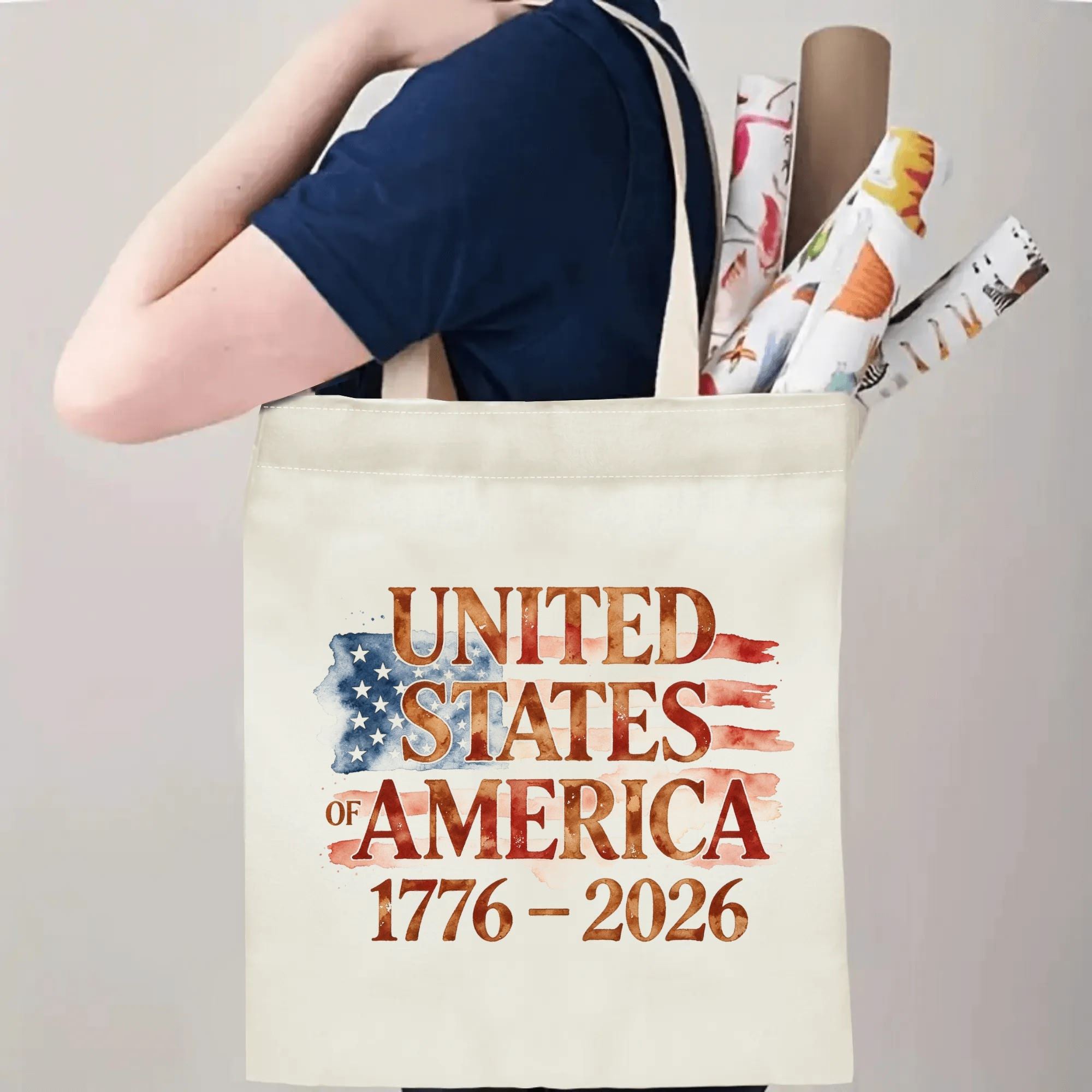 Person wearing the "UNITED STATES OF AMERICA 1776–2026" tote bag over their shoulder, showing its use as a carryall bag.