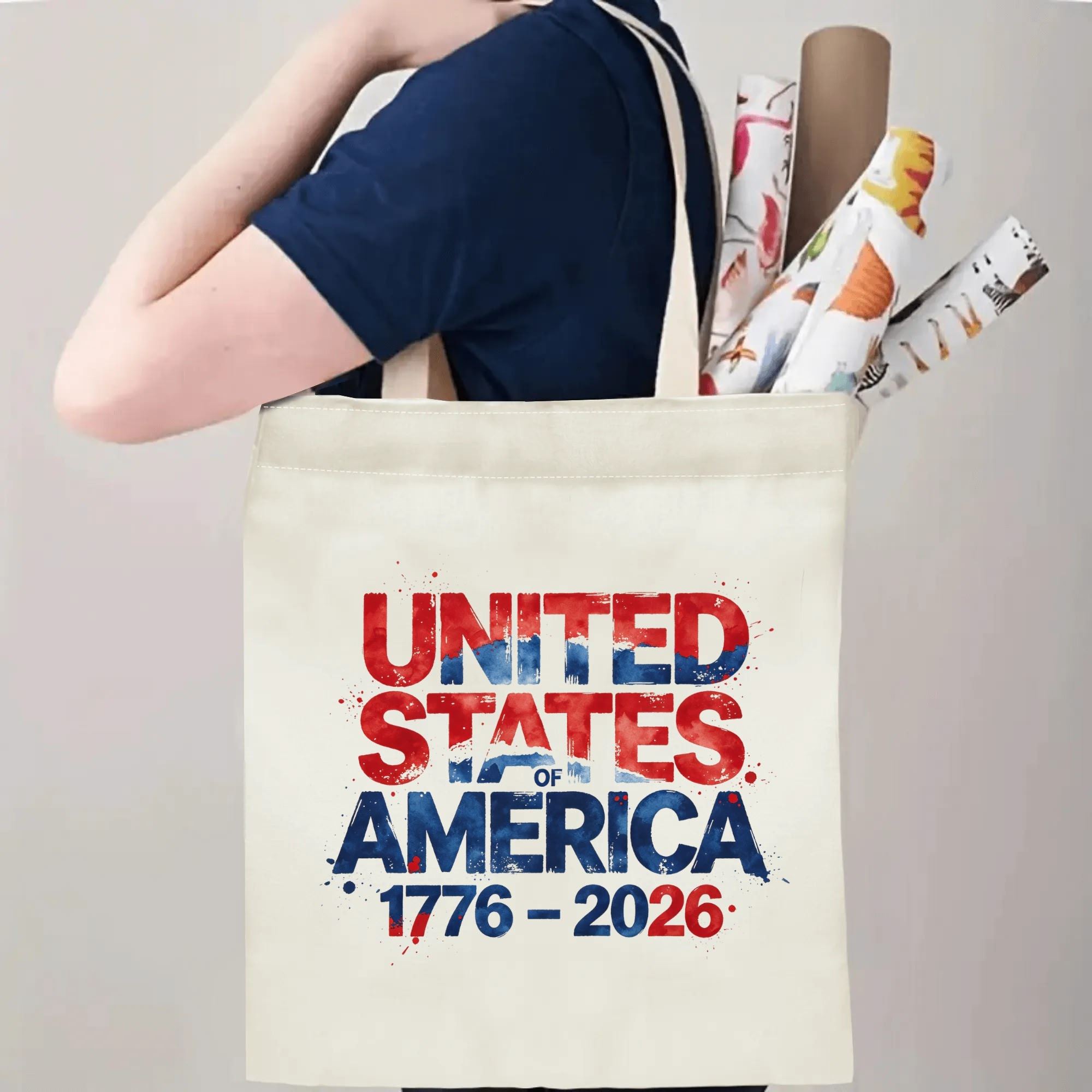 Person wearing the "UNITED STATES OF AMERICA 1776–2026" tote bag over their shoulder, showing its use as a carryall bag.