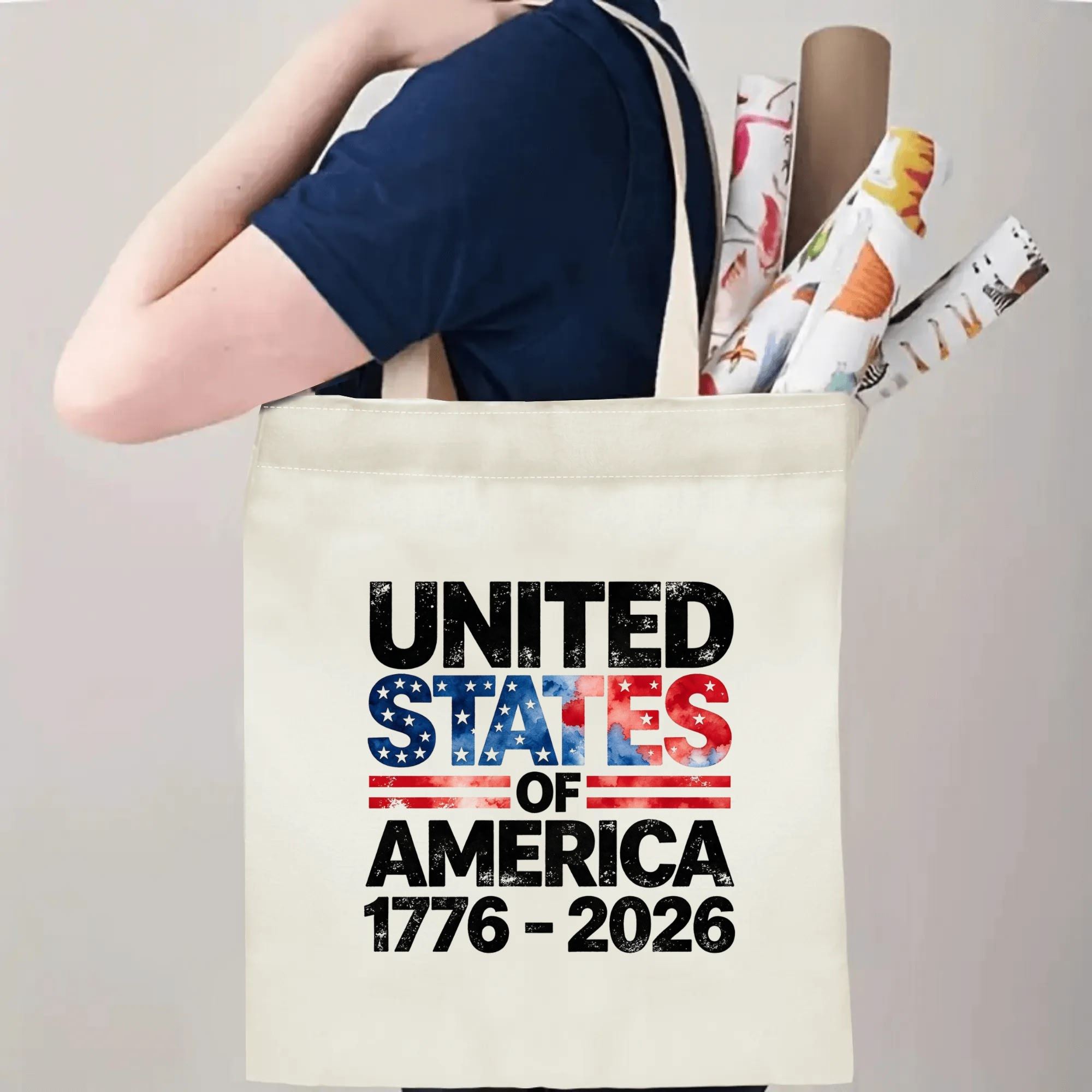 Person wearing the "UNITED STATES OF AMERICA 1776–2026" tote bag over their shoulder, showing its use as a carryall bag.