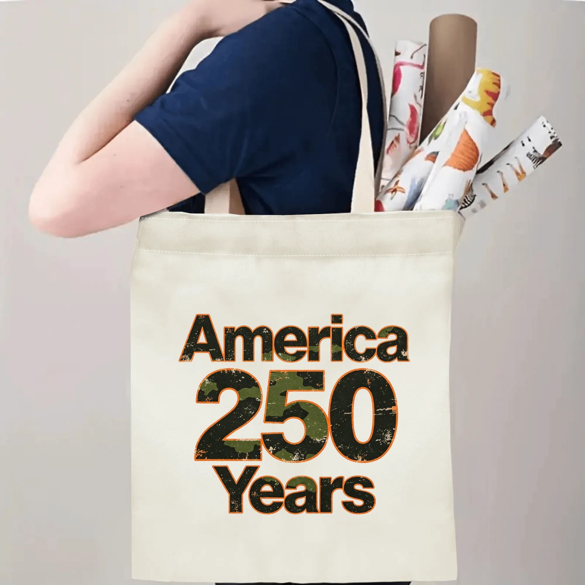 Person wearing the tote bag over their shoulder, showing the print from the side, with rolled-up items peeking out.