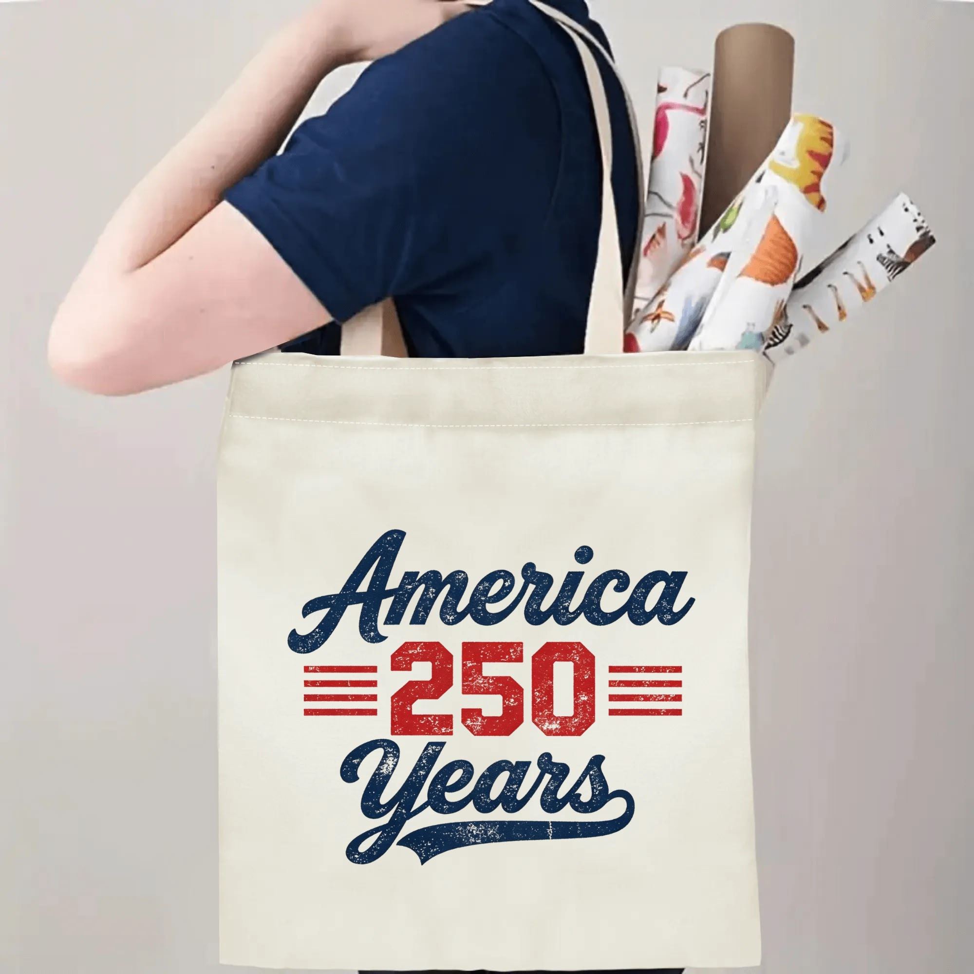 Person wearing the tote bag over their shoulder, showing the print from the side, with rolled-up items peeking out.