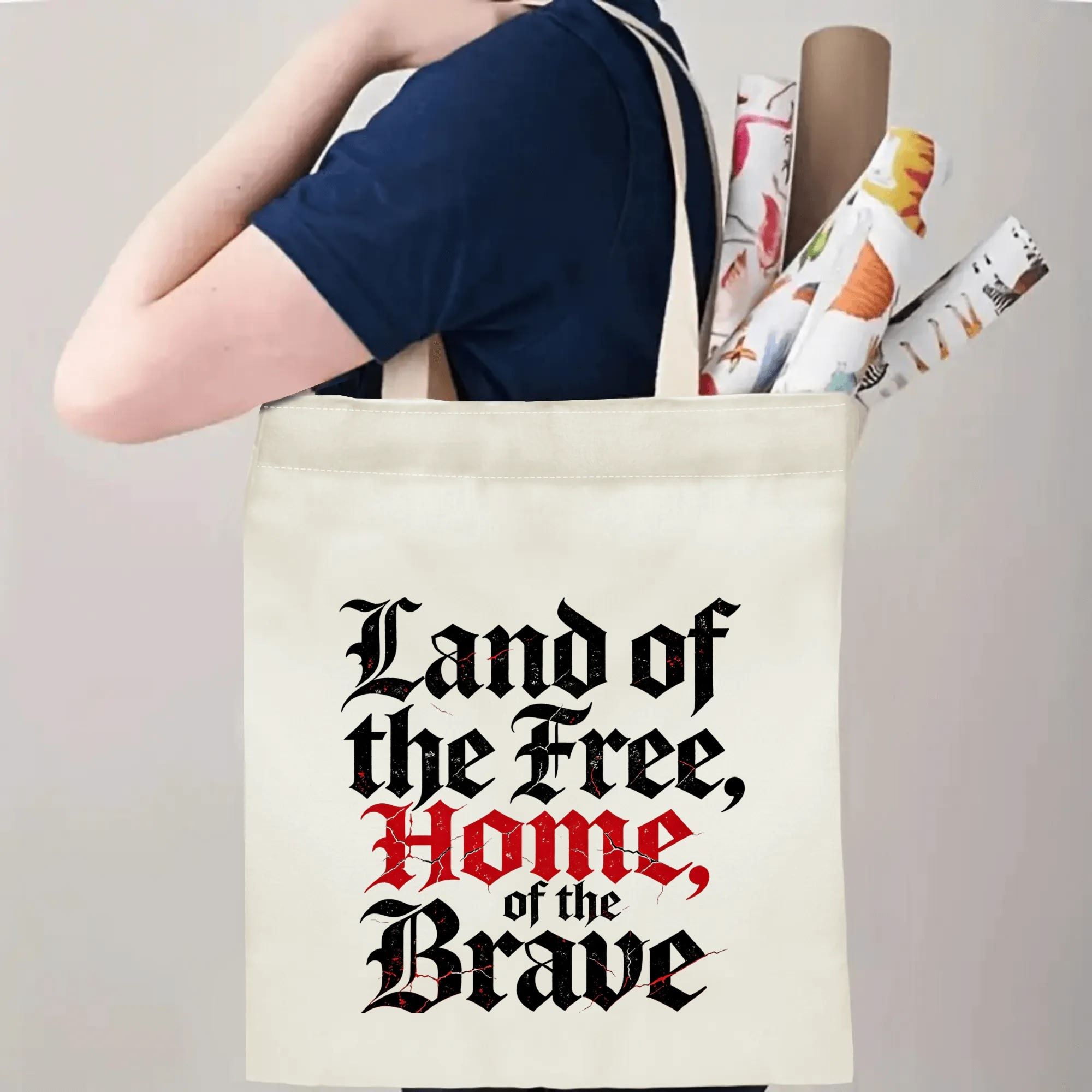 Person wearing the tote bag over their shoulder, showing the print from the side, with rolled-up items peeking out.