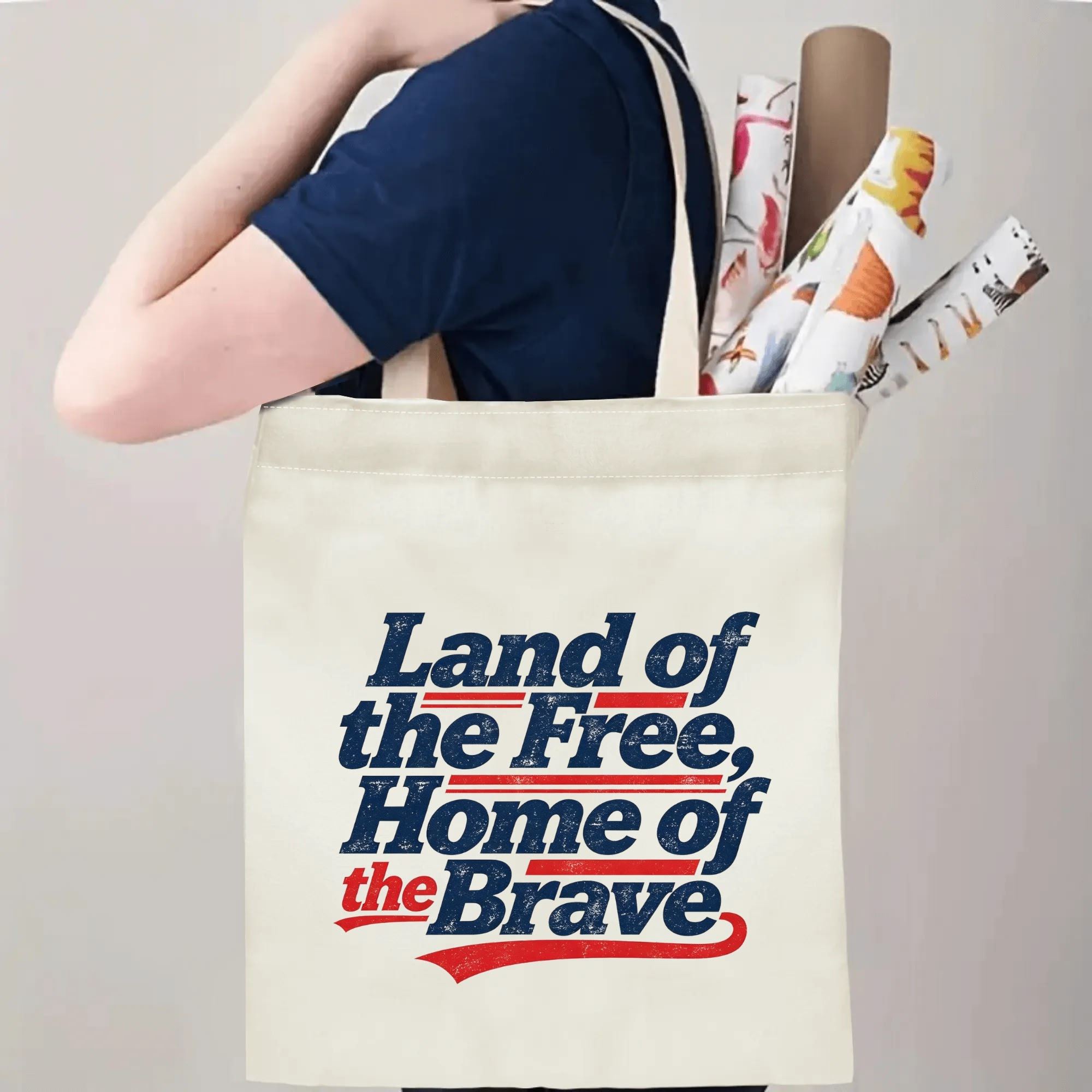 Person wearing the tote bag over their shoulder, showing the print from the side, with rolled-up items peeking out.