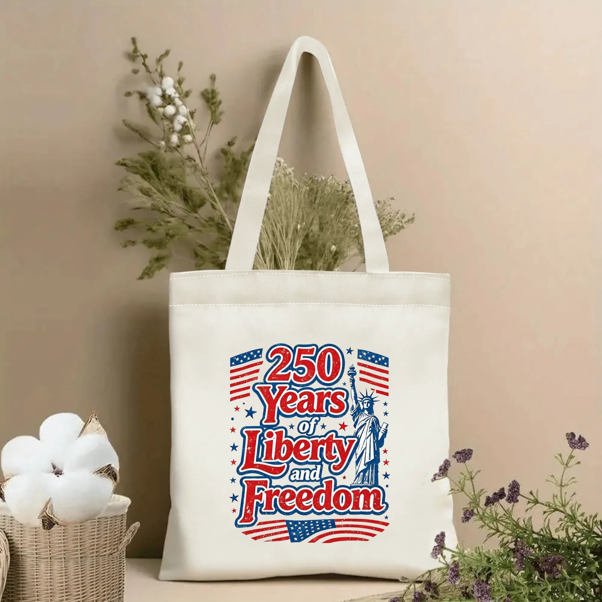 Lifestyle shot of the tote bag featuring a vintage "250 Years of Liberty and Freedom" print with the Statue of Liberty and American flags, styled with dried flowers.