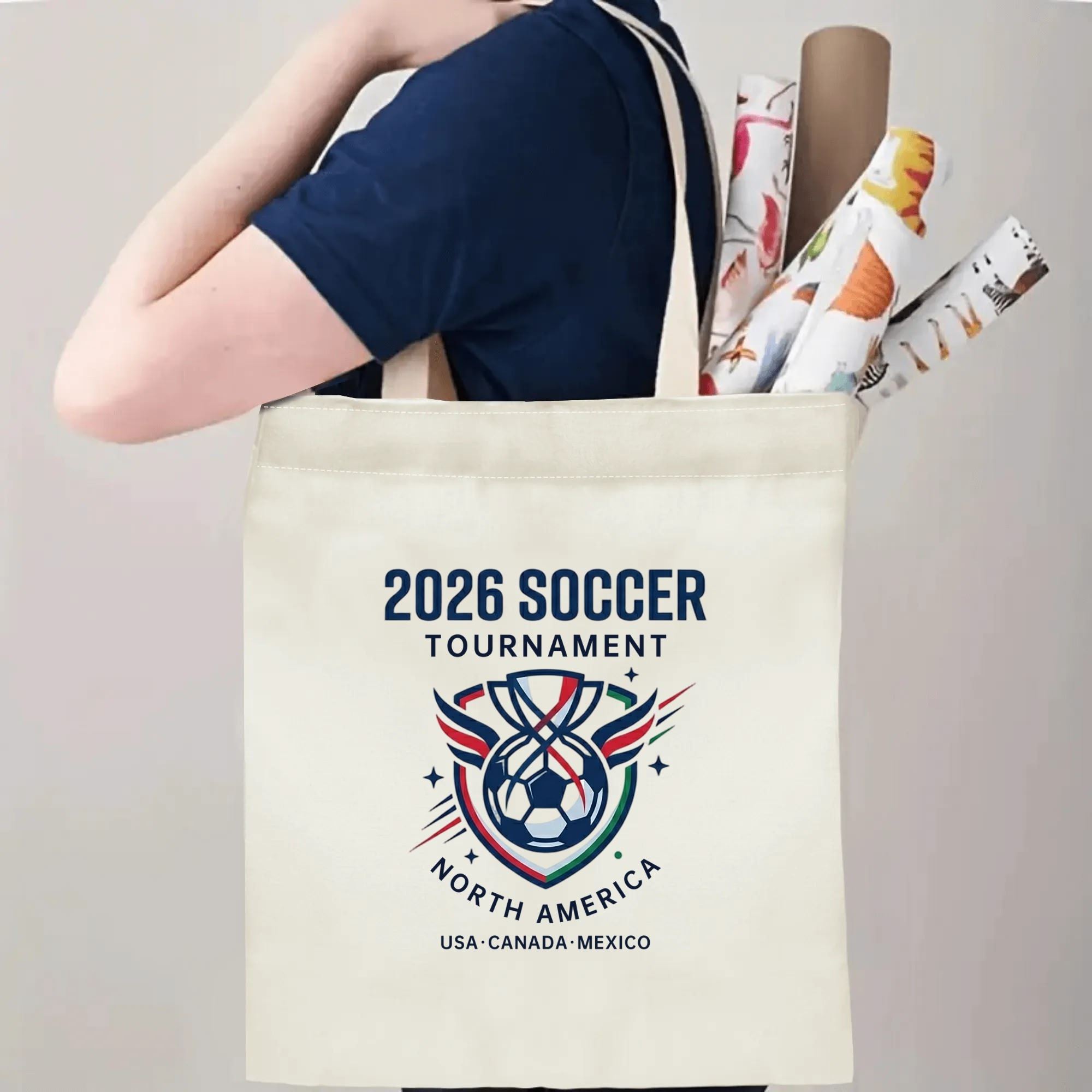 Person slinging 2026 USA Canada Mexico wing trophy soccer badge canvas tote bag over shoulder, large capacity athletic football supporter carry bag for stadium outings