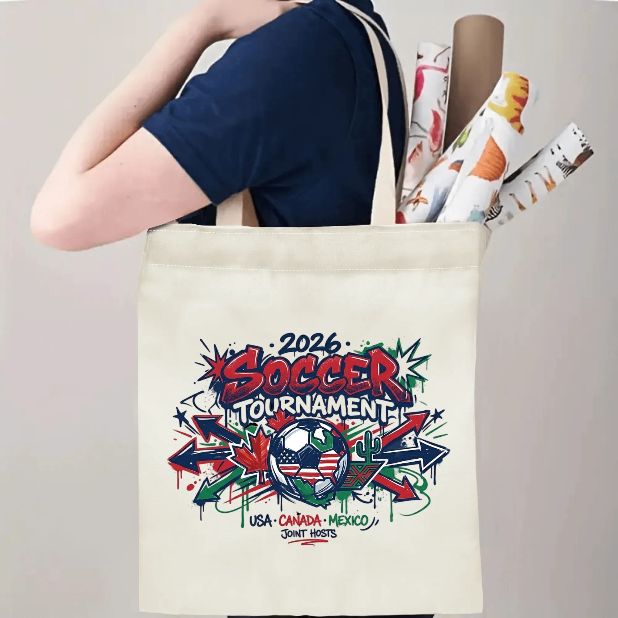 Person carrying 2026 USA Canada Mexico arrow graffiti soccer tote bag over shoulder, large capacity urban football supporter bag for stadium trips