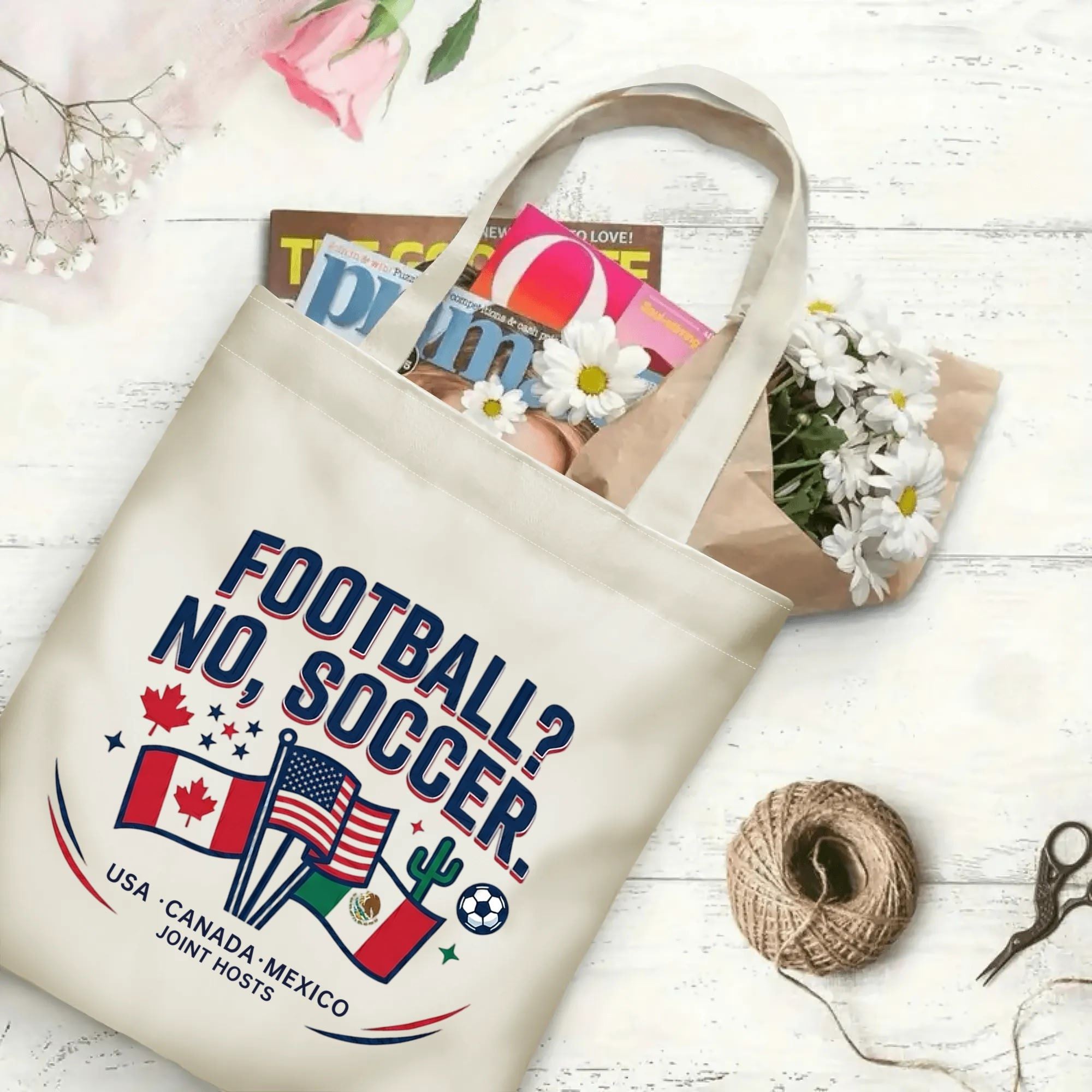 Retro varsity soccer quote & country flag graphic canvas tote bag laid flat with magazines and daisies, reusable casual sport fan daily shopping bag