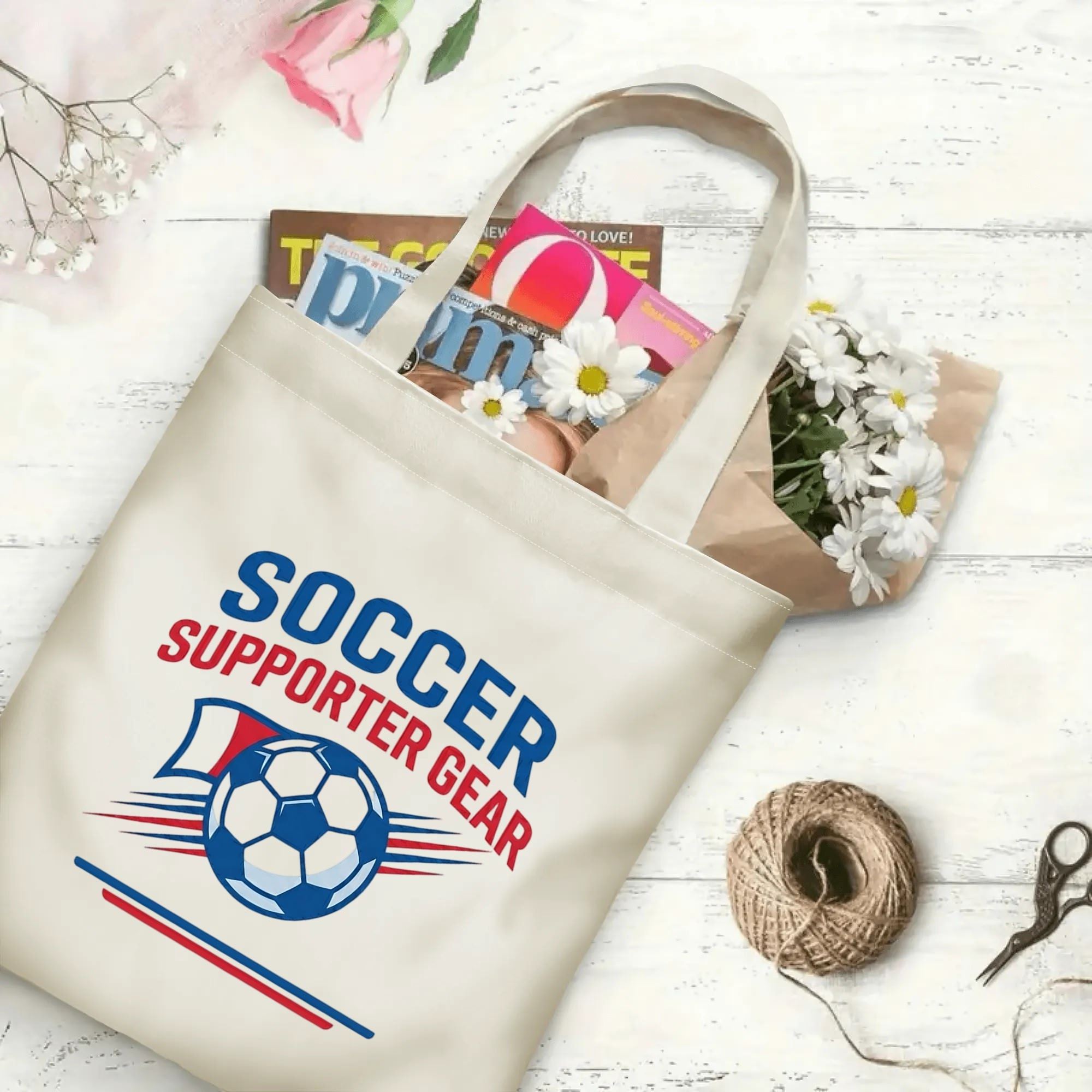Varsity two-tone soccer slogan graphic canvas tote bag laid flat with magazines and daisies, reusable casual athletic fan daily shopping bag