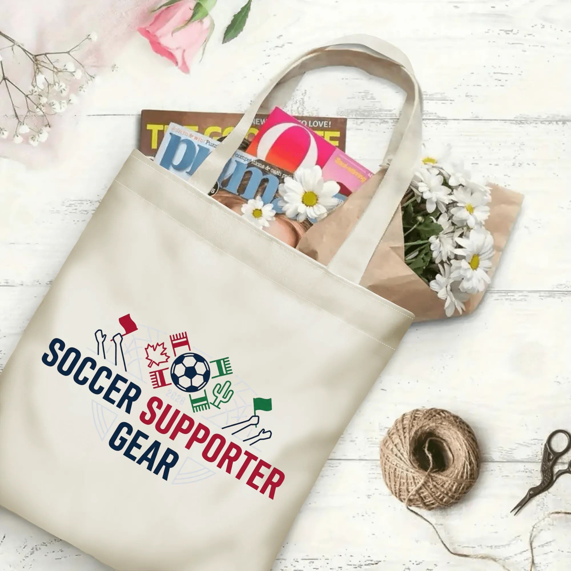 Minimalist cheering fan hands soccer graphic canvas tote bag laid flat with magazines, daisies and twine, reusable sport fan daily shopping bag