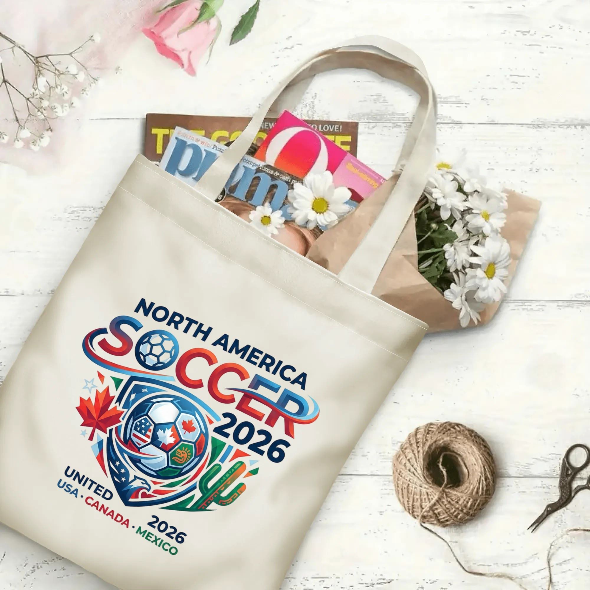 Dynamic swirl gradient letter soccer globe graphic canvas tote bag laid flat with magazines and daisies, reusable contemporary gameday sport fan daily shopping bag