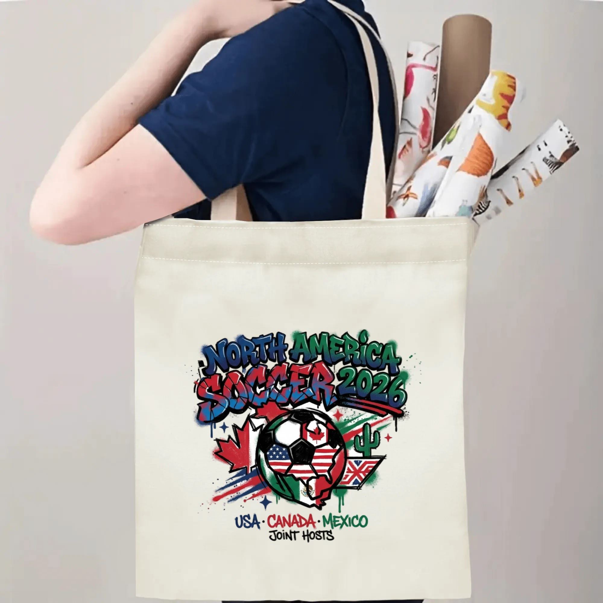 Person slinging 2026 World Cup USA Canada Mexico graffiti soccer graphic polyester canvas tote bag over shoulder, large capacity trendy football supporter carry bag for stadium outings