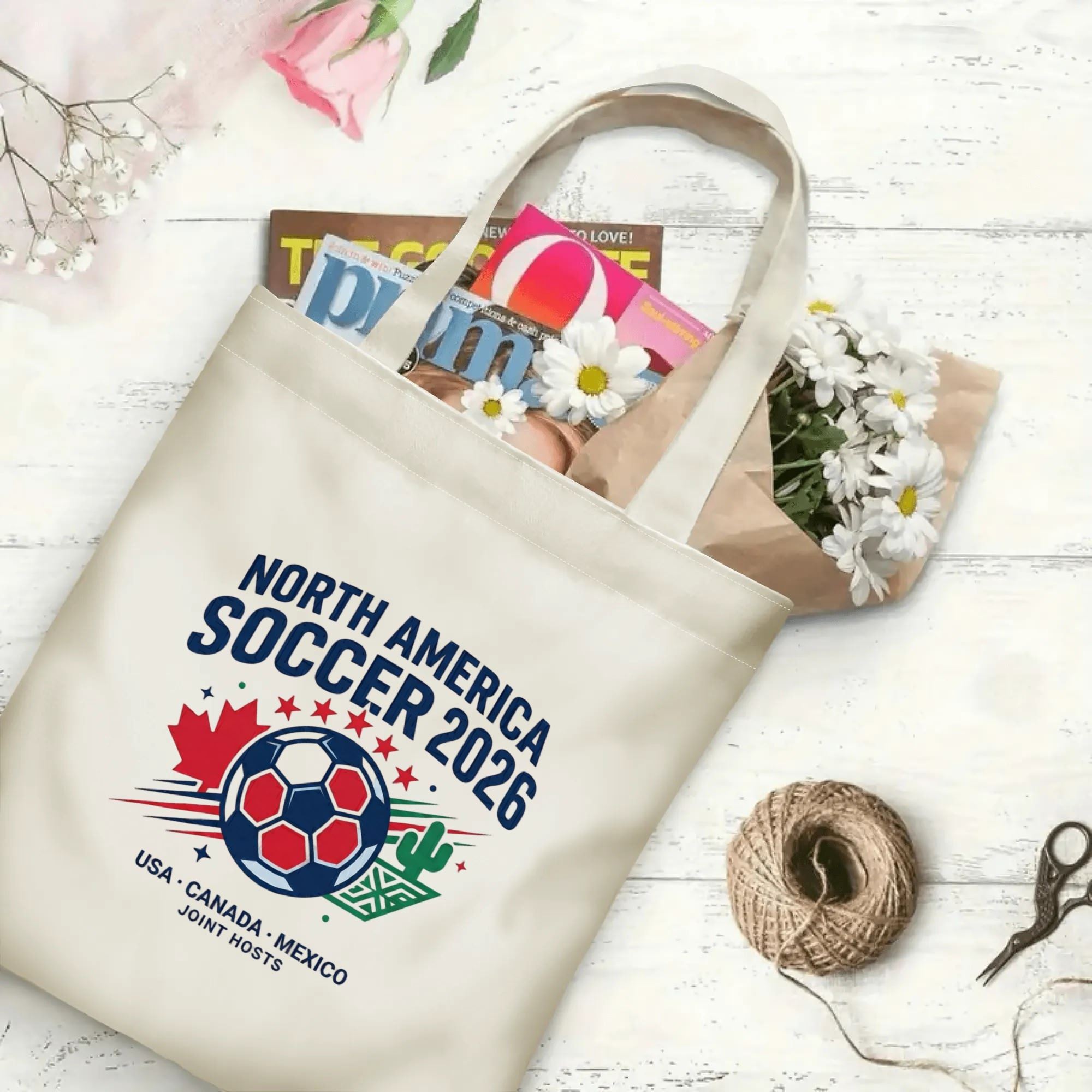 Vintage varsity soccer crest graphic canvas tote bag laid flat with magazines and daisies, reusable classic sport fan daily shopping bag