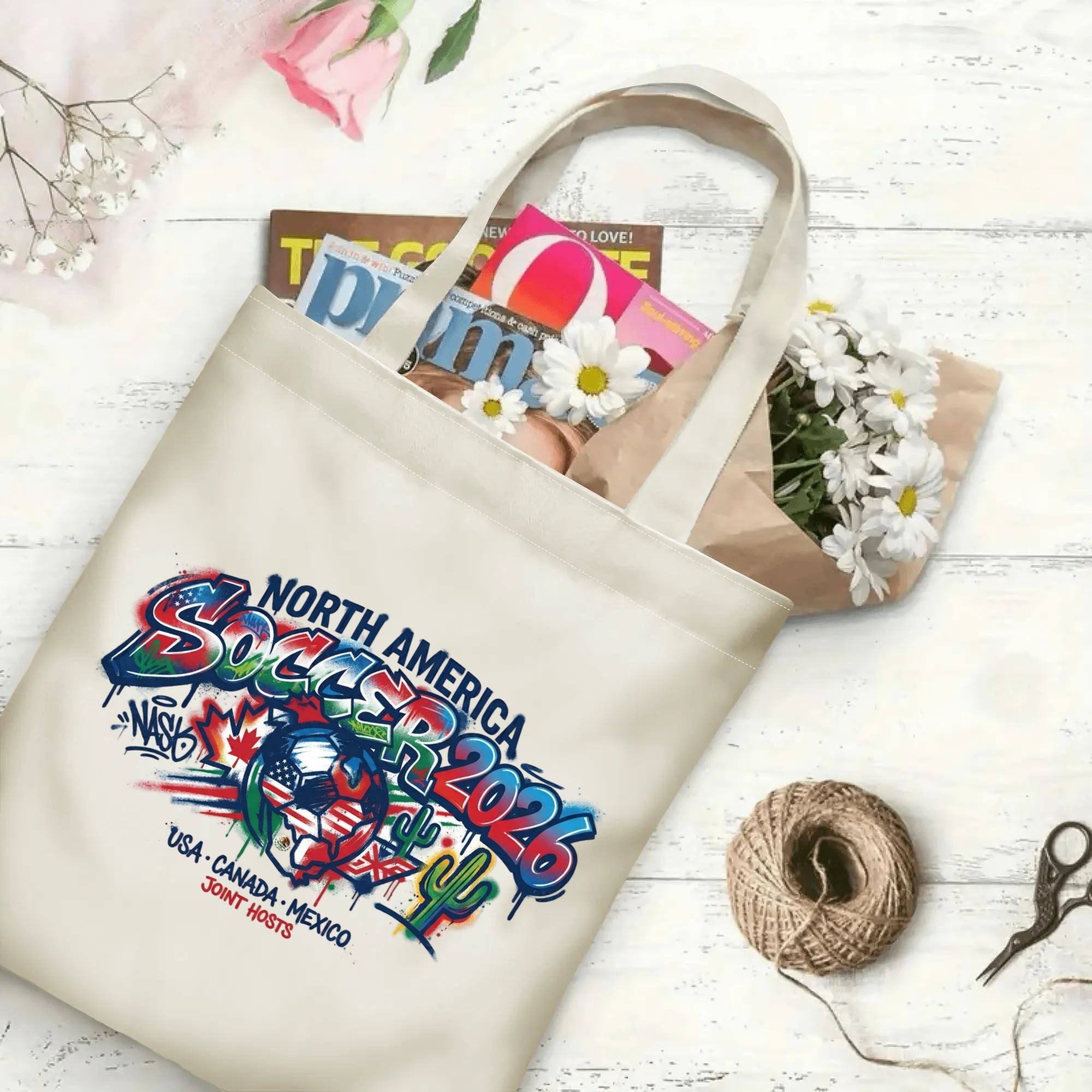 Color splash graffiti maple cactus flag soccer graphic canvas tote bag laid flat with magazines and daisies, reusable urban gameday sport fan daily shopping bag