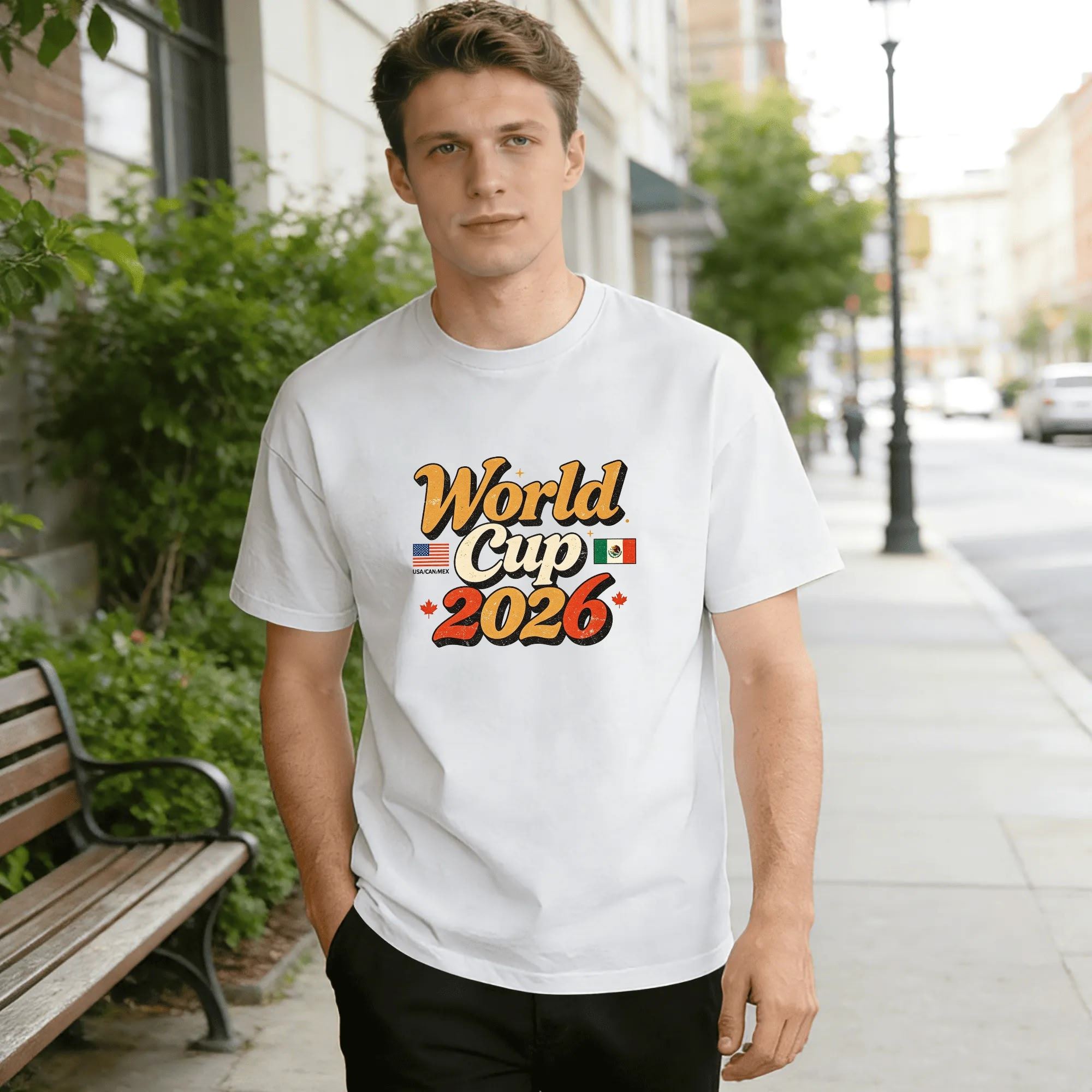 Lifestyle shot of a man wearing the white “World Cup 2026” retro script T-shirt, outdoors in an urban setting