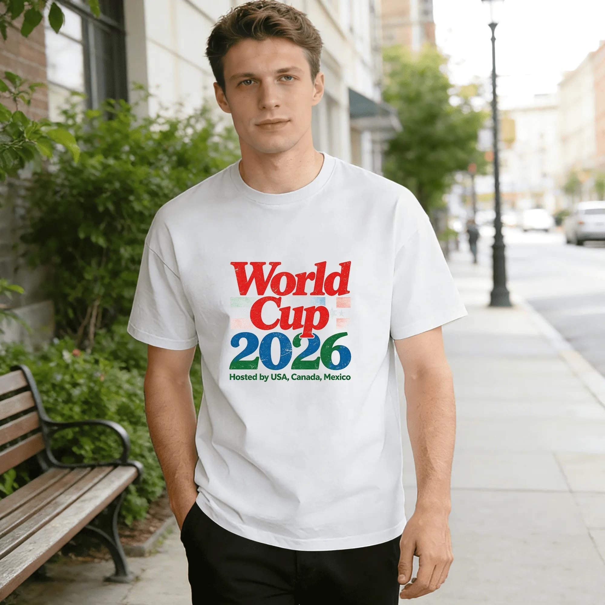 Lifestyle shot of a man wearing the white “World Cup 2026” retro color script T-shirt, outdoors in an urban setting