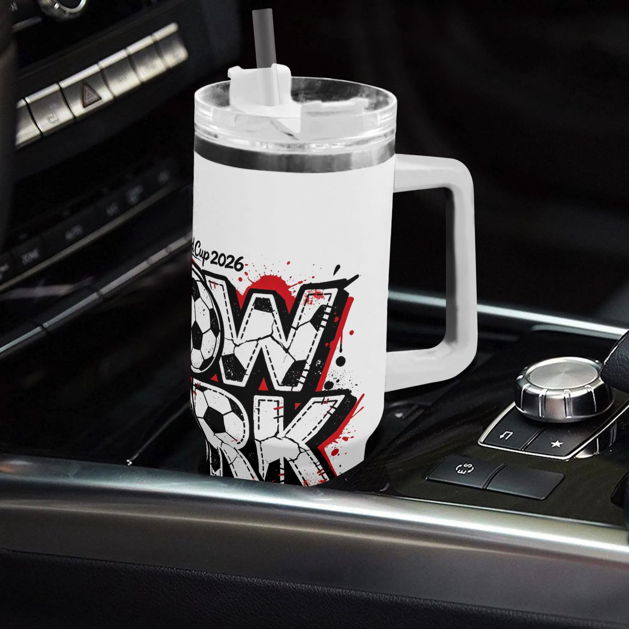 White 40oz insulated tumbler in a car cup holder, featuring a graffiti-style "New York World Cup 2026" print with soccer ball lettering and red splatters.