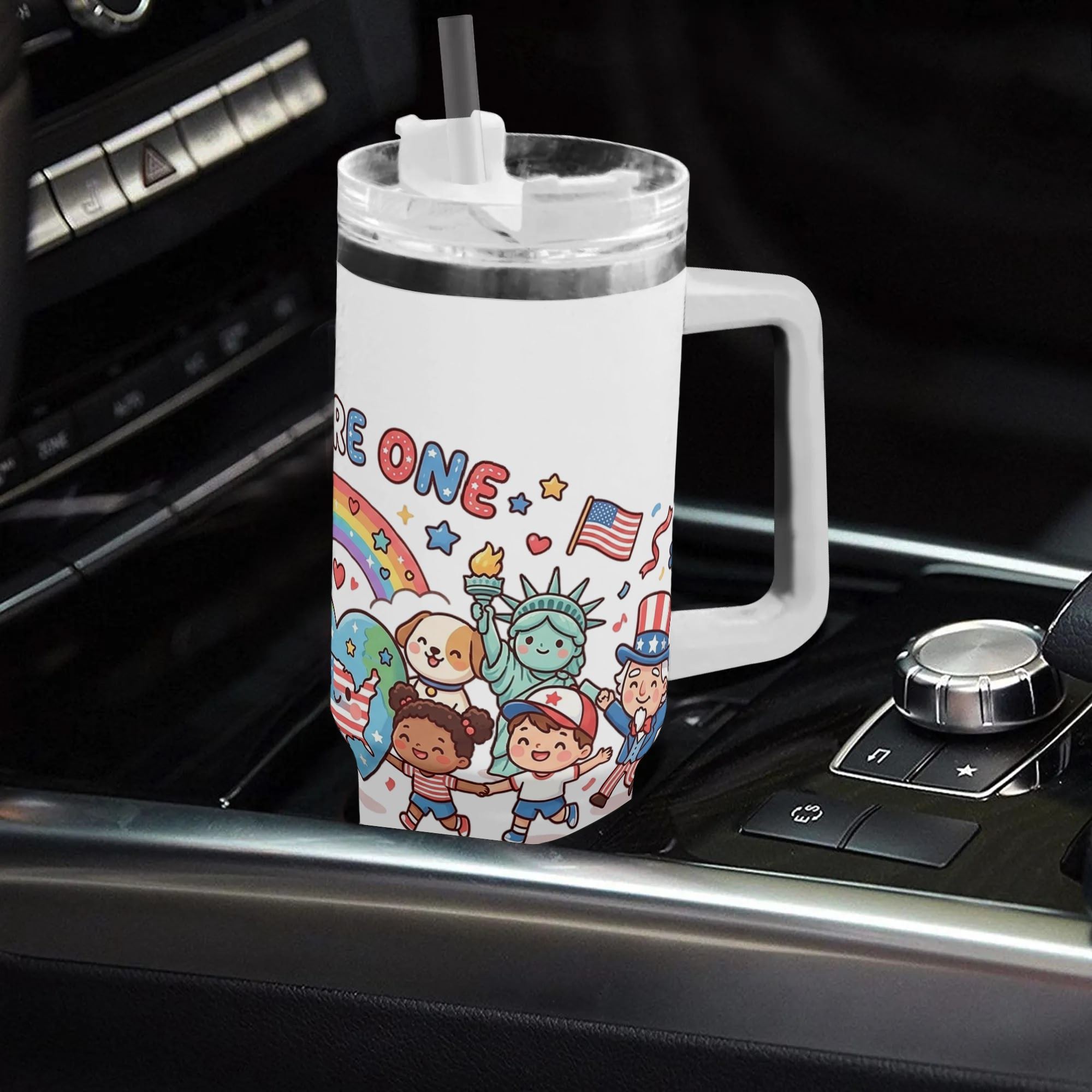 Car interior lifestyle shot: 40oz white handle tumbler with full-wrap cute cartoon patriotic print "WE ARE ONE FOREVER AMERICA", placed on vehicle gear shift console, daily road trip insulated water cup