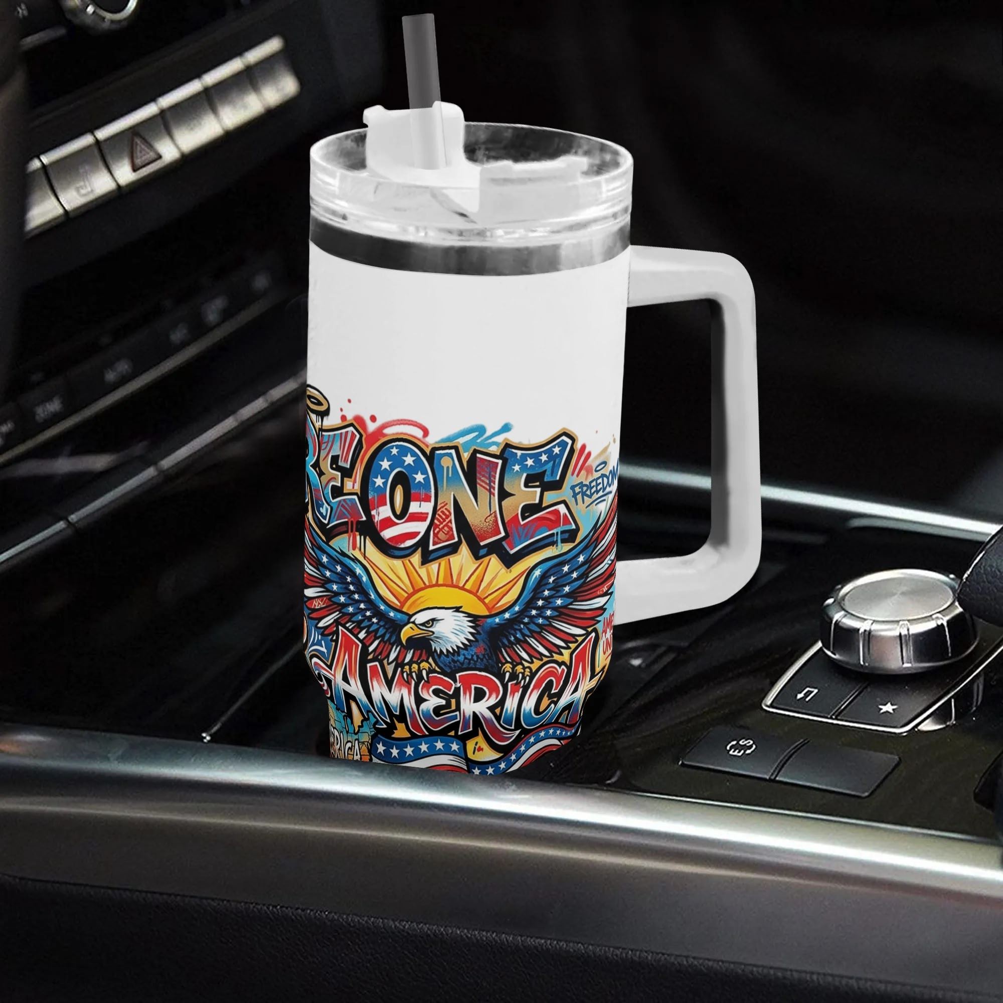 White 40oz handle tumbler with colorful We Are One Forever America bald eagle graffiti print placed in car gear shift, USA 250th bicentennial insulated travel mug