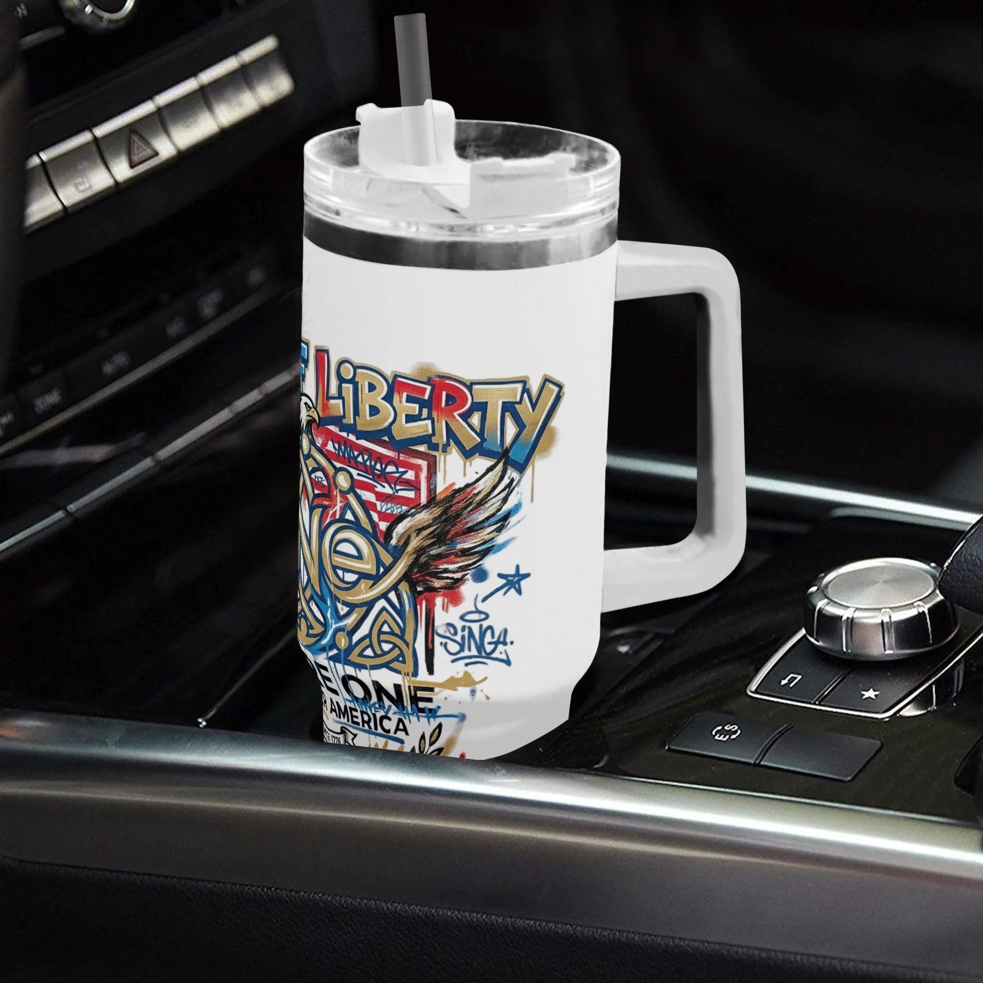 White 40oz handle tumbler with Born of Liberty We Are One eagle graffiti print placed in car gear shift, USA 250th bicentennial insulated travel mug