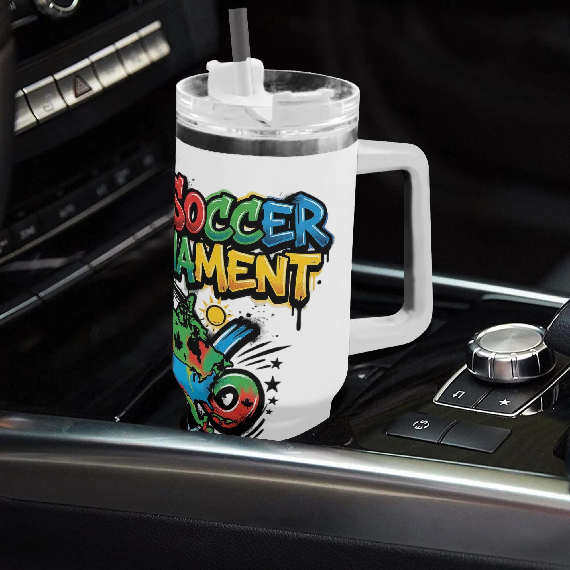 White 40oz handled insulated tumbler printed with colorful drip graffiti North America map soccer graphic, placed on car gear shift console, 2026 World Cup fan stainless steel travel mug for driving