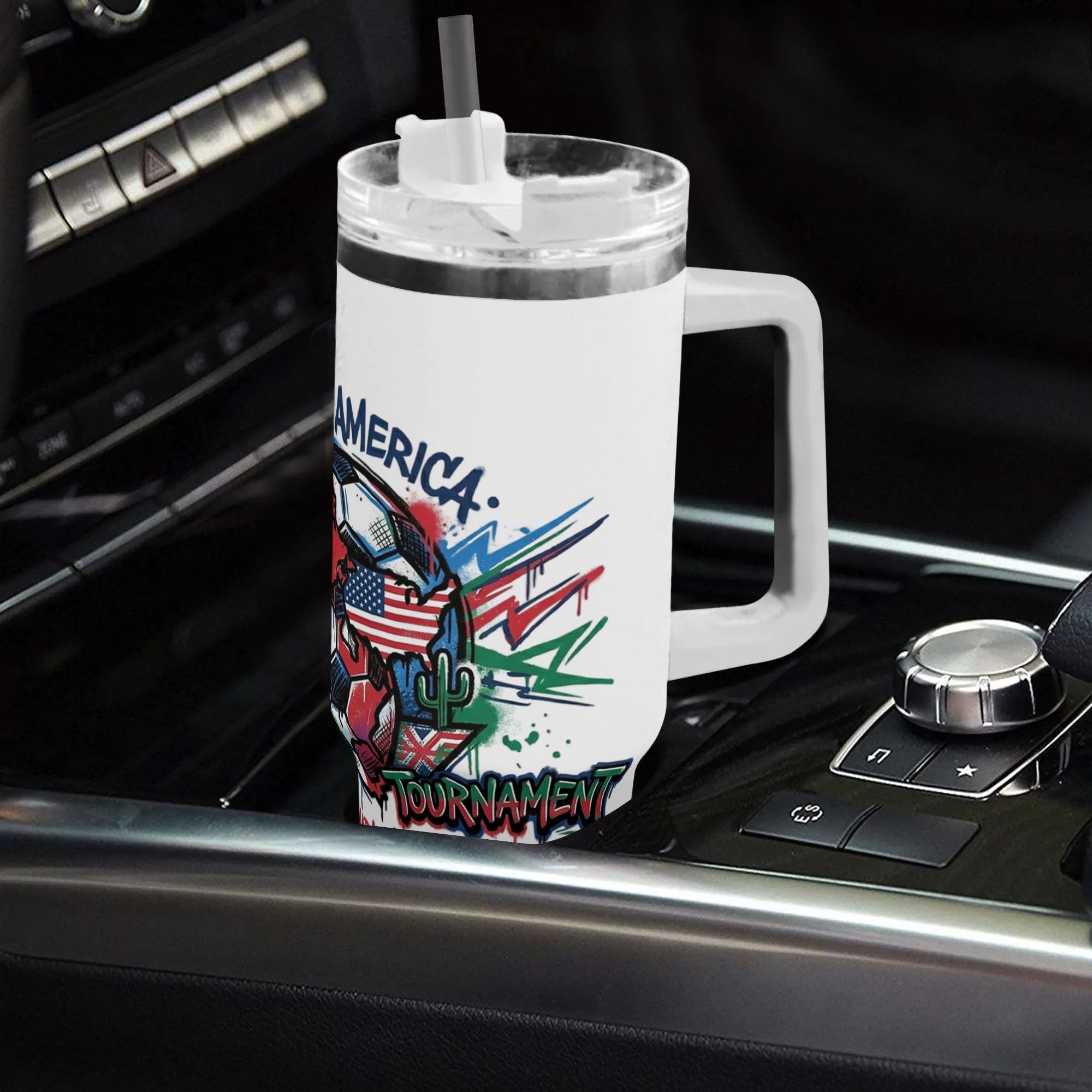 White 40oz handled insulated tumbler with colorful drip graffiti North America three host soccer globe print, placed in car gear shift console, 2026 World Cup fan stainless steel travel mug for driving