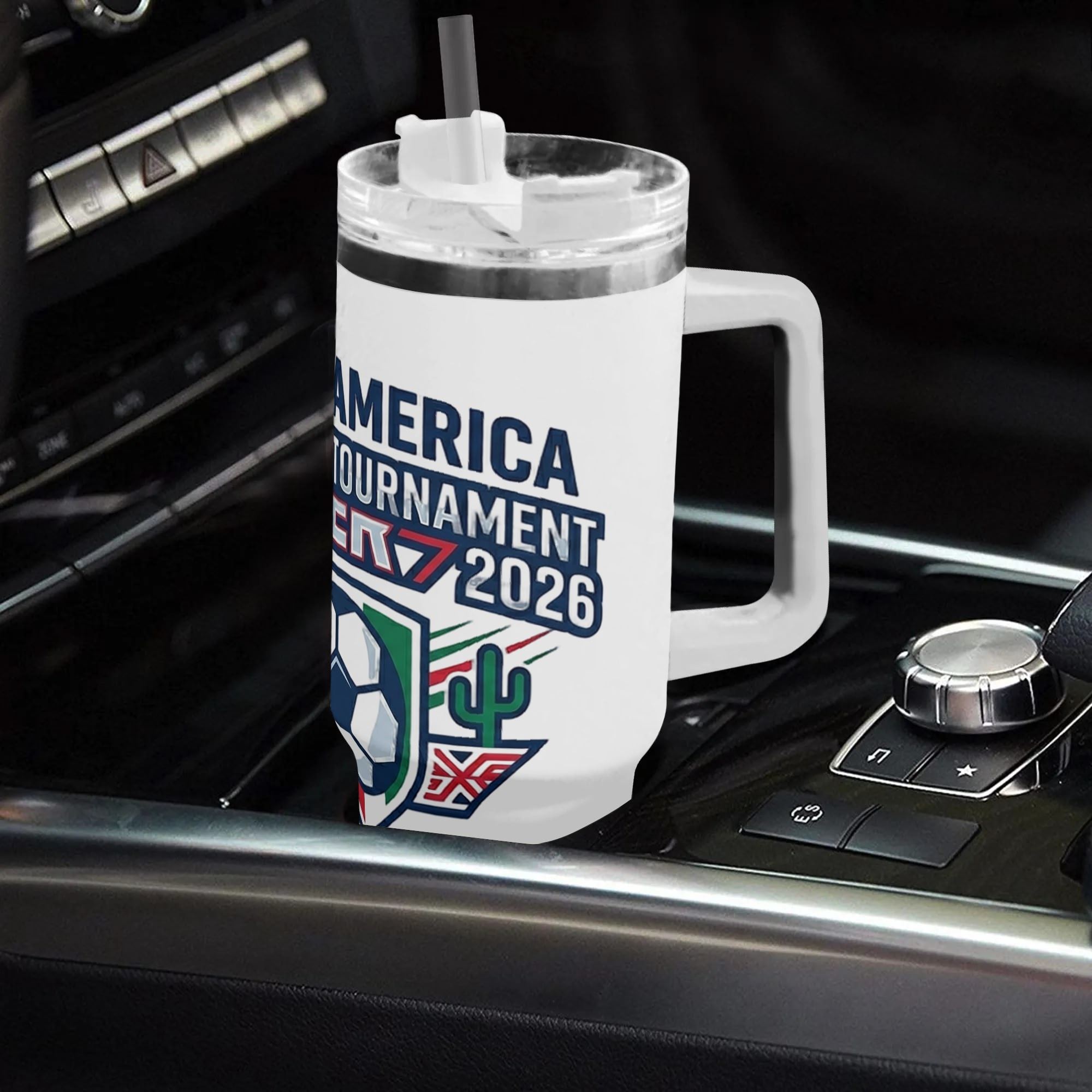White 40oz handled insulated tumbler printed with vintage North America soccer shield crest graphic, placed on car gear shift console, 2026 World Cup fan stainless steel travel mug for driving